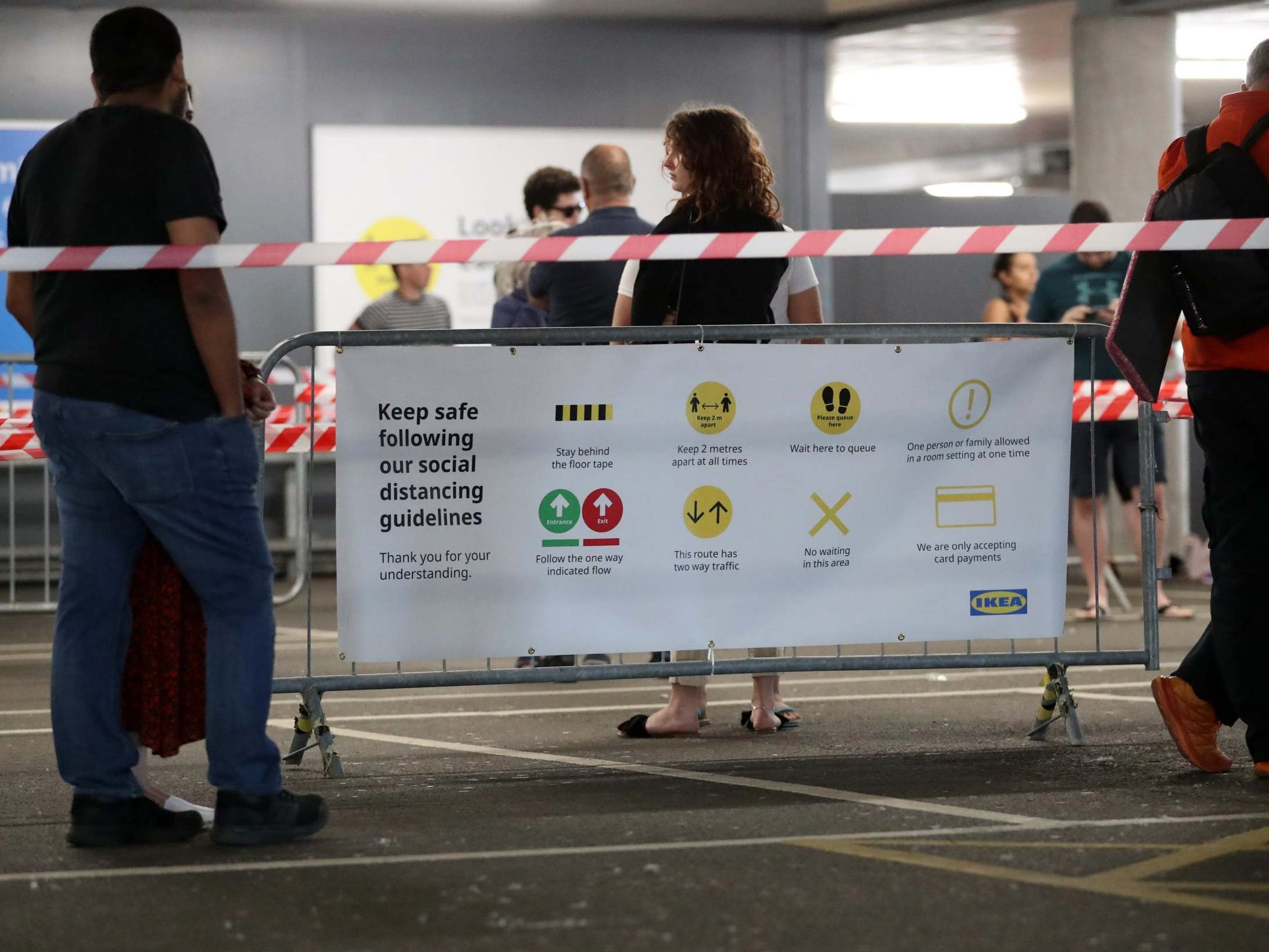 A sign with social distancing guidelines is seen as customers queue to go into IKEA Milton Keynes (Getty)