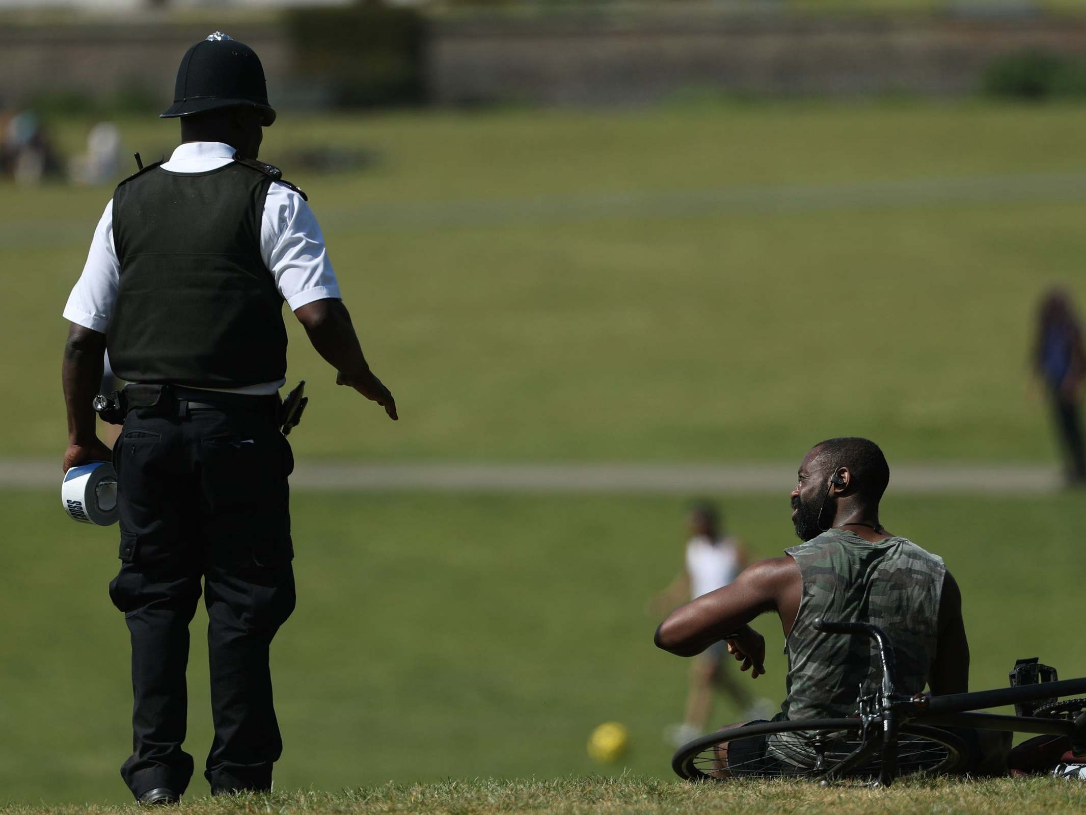 A police officer moves sunbathers in Greenwich Park, London, on 9 May