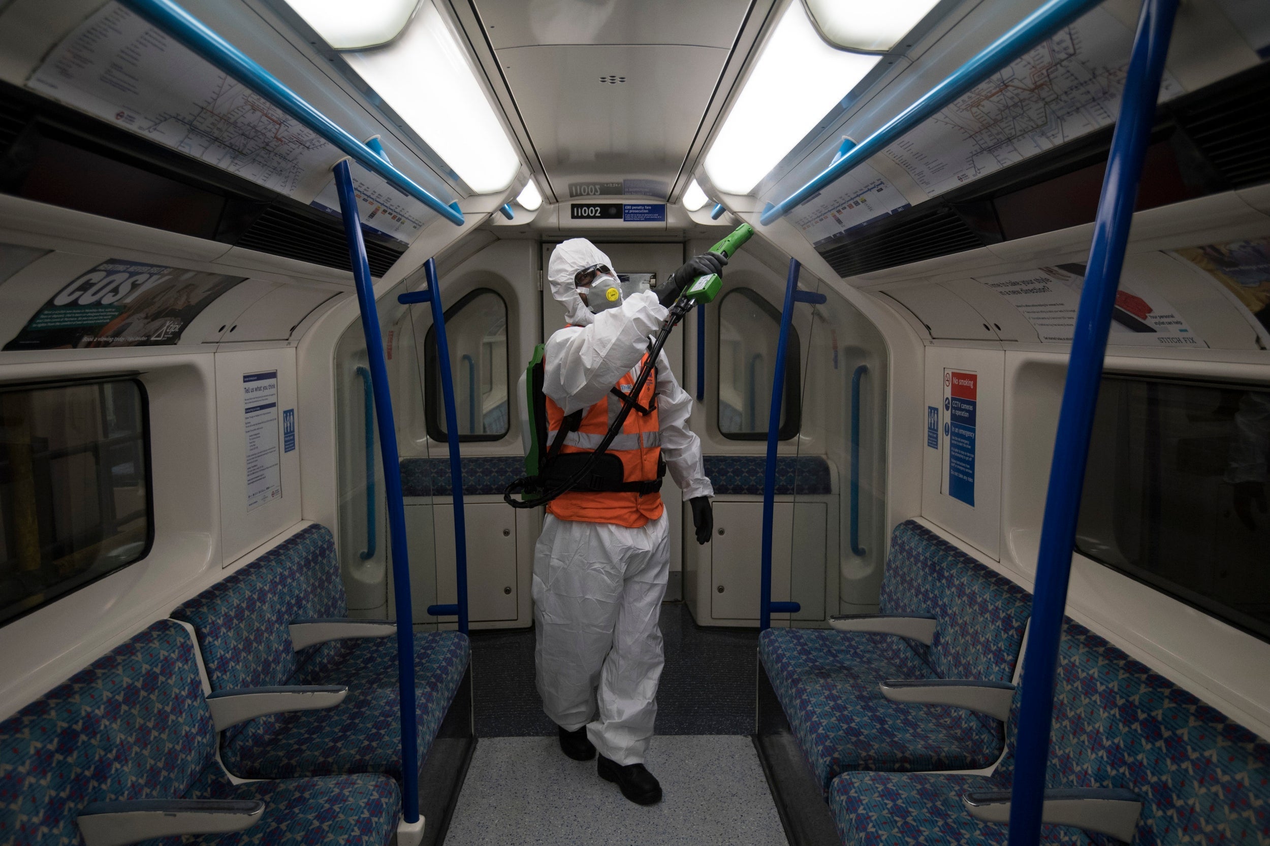 TfL worker Noureddine Aouf sprays an anti-viral surface sanitiser inside a Victoria line Tube train