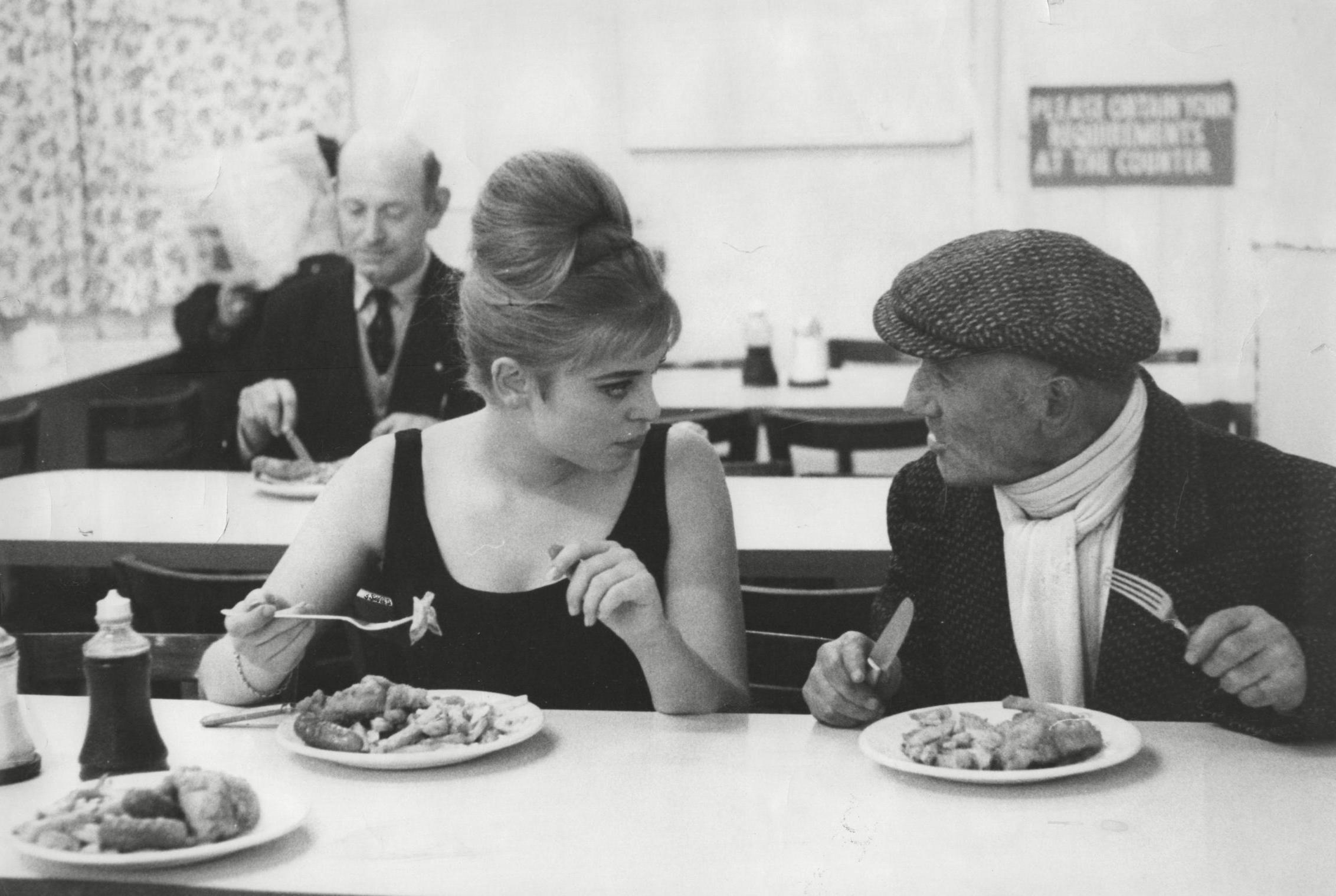 Actress Edina Ronay and her uncle Leny tuck into fish and chips in a shop in the Mile End Road, East London (28 April 1963)