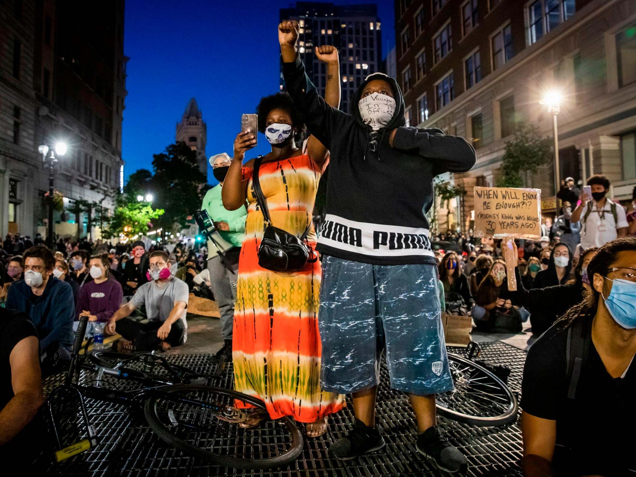 Demonstrators raise their fists during a Sit Out the Curfew in Oakland, California