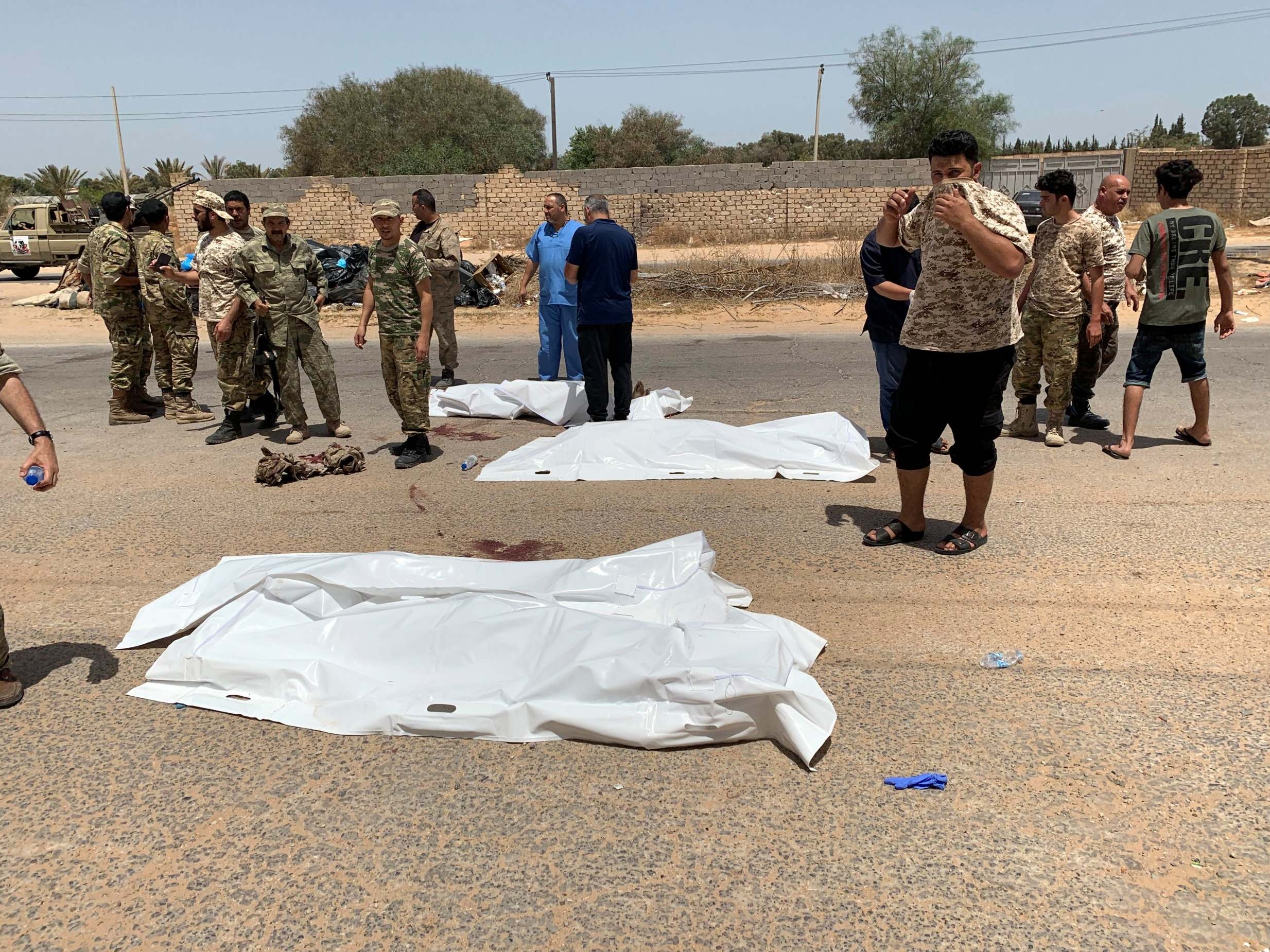 GNA fighters gather near covered bodies after regaining control of Tripoli (Reuters)