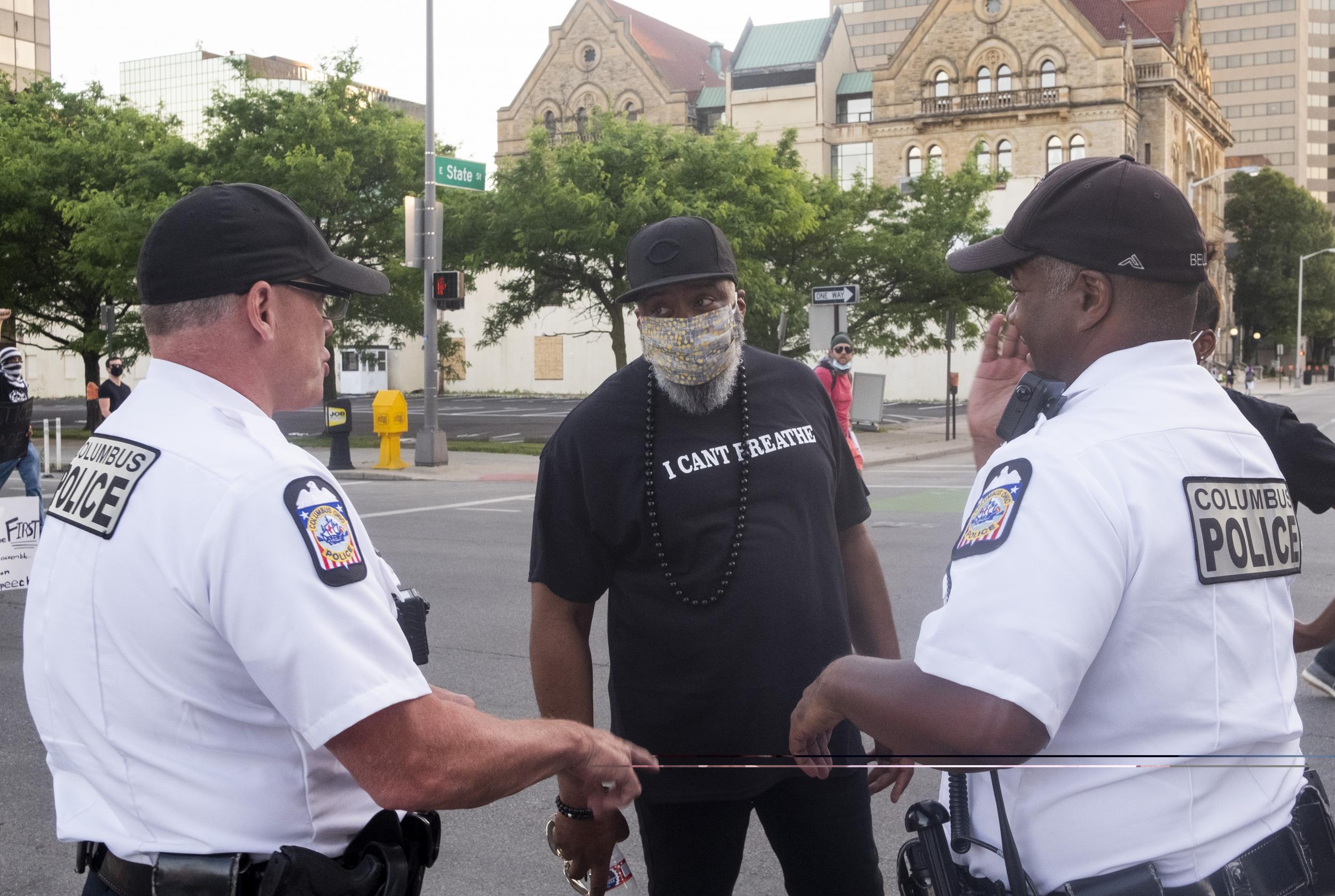 Columbus Police officers speak to a protester as thousands march towards the Statehouse in downtown Columbus, Ohio