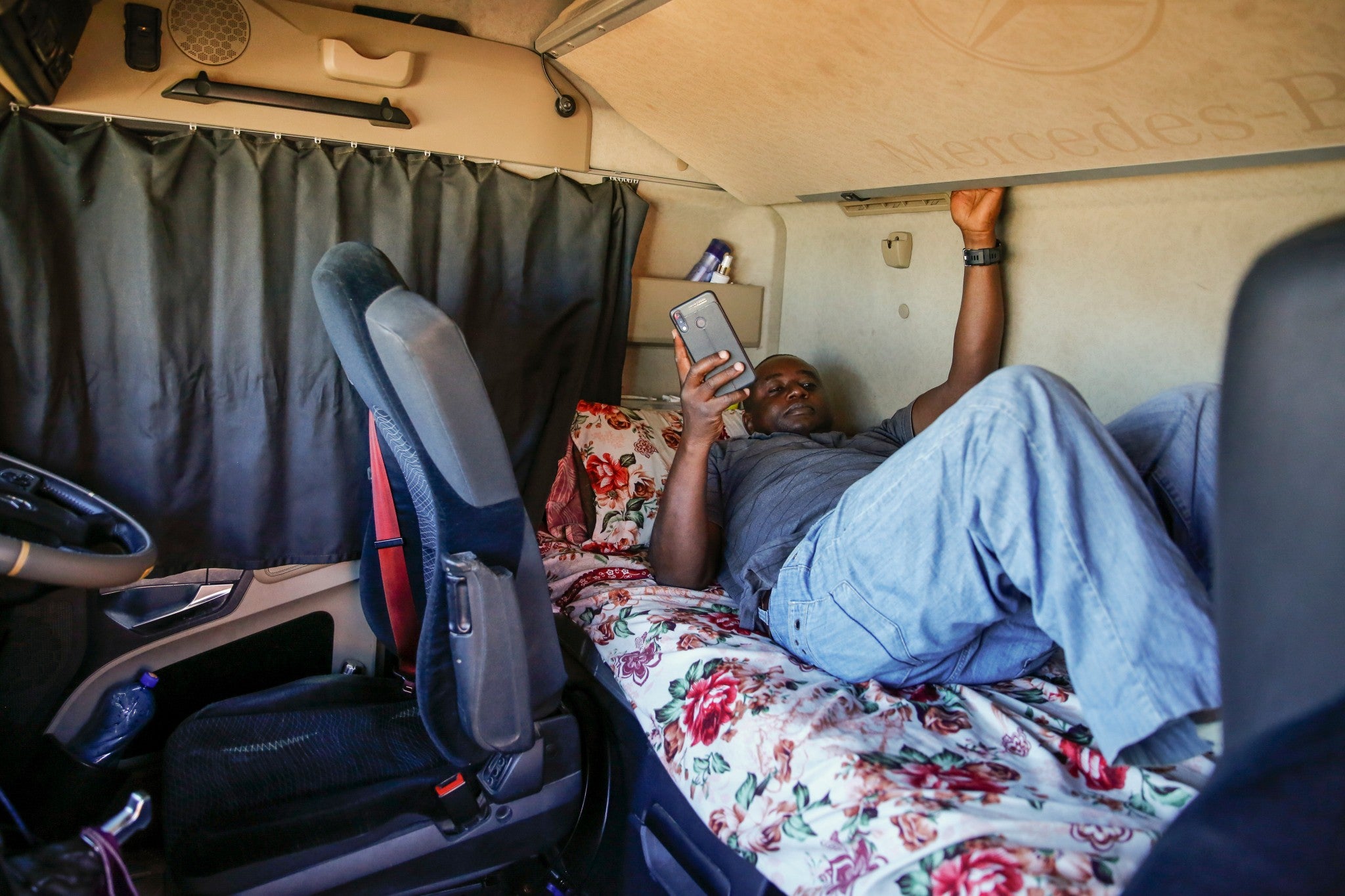 Kenyan truck driver Abdulkarim Rajab lies down in the cabin of his truck as he waits for his papers to be cleared and verified so that he can enter Kenya