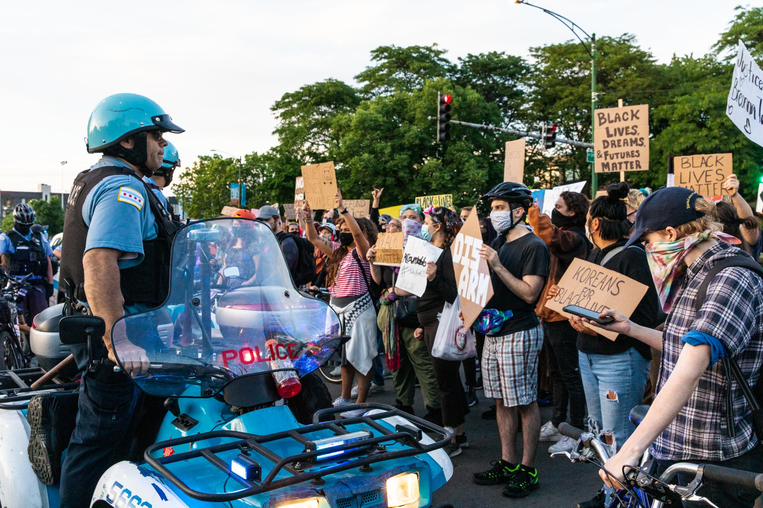 Protesters chant and wave signs at the Chicago Police Department during a protest