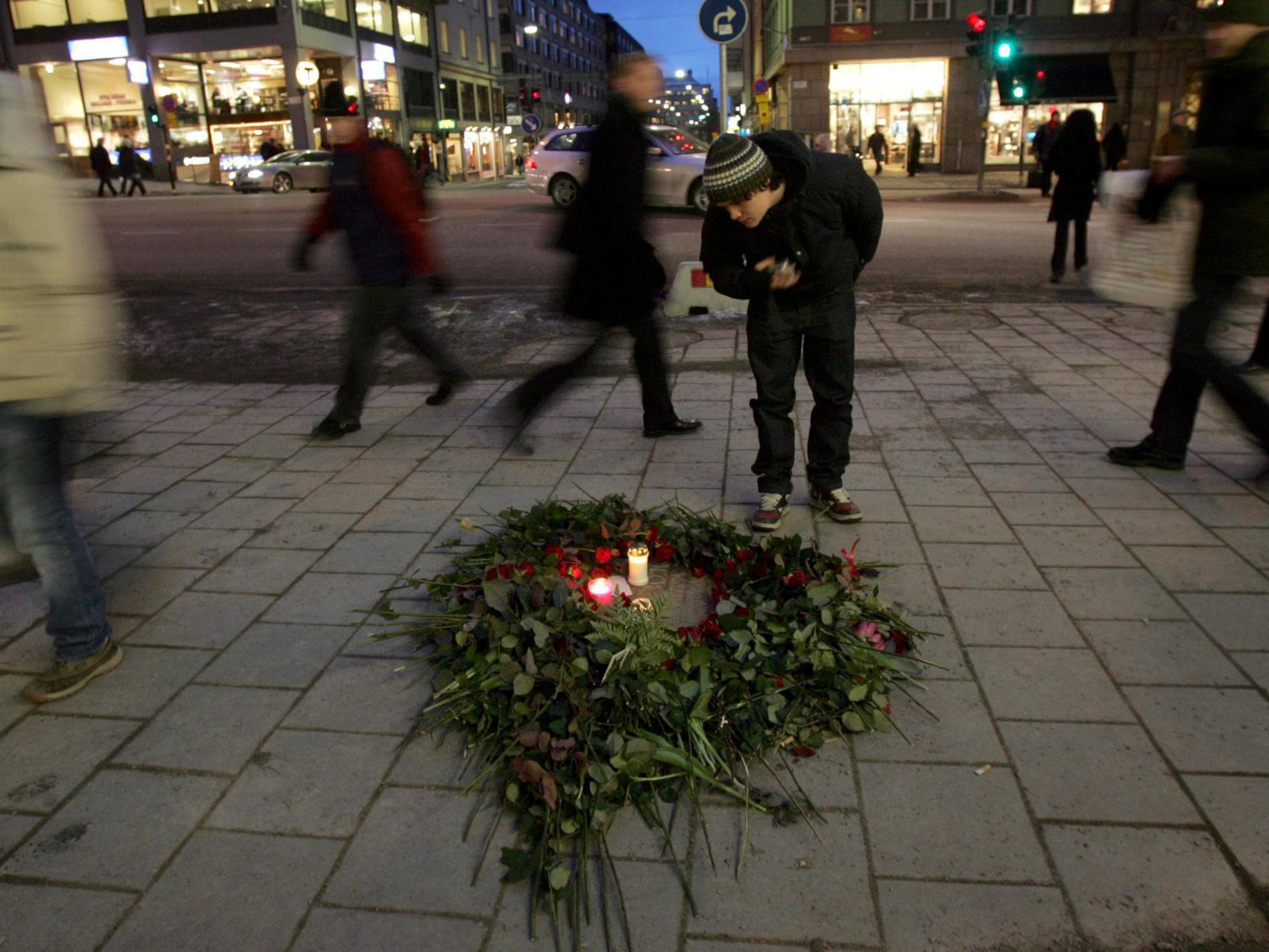 A bunch of roses and lit candles lie on the spot where Olof Palme was gunned down in Stockholm