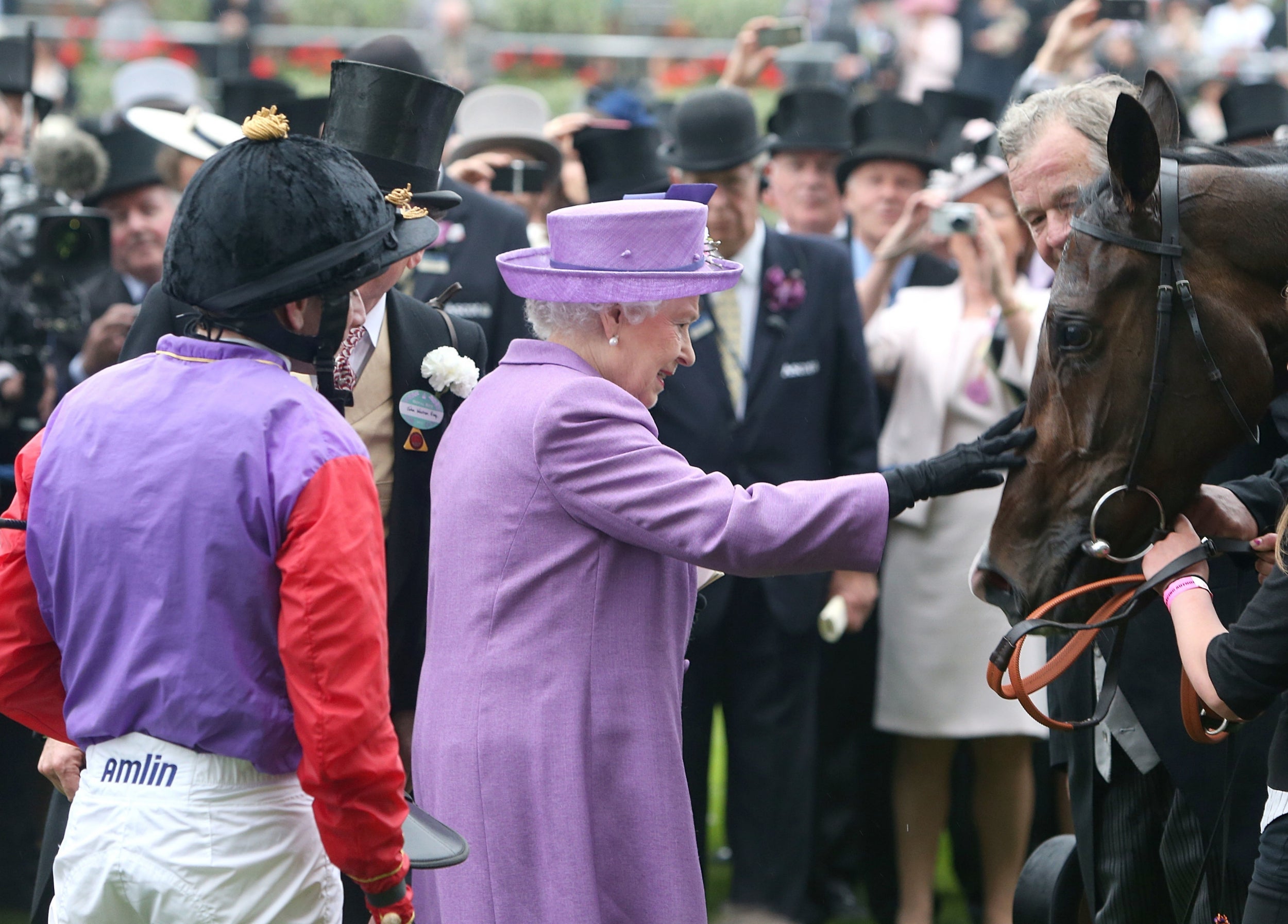 Queen Elizabeth II pats her horse Estimate after it won the Gold Cup ridden by jockey Ryan Moore (left) during Ladies’ Day at Royal Ascot, 26 June 2013