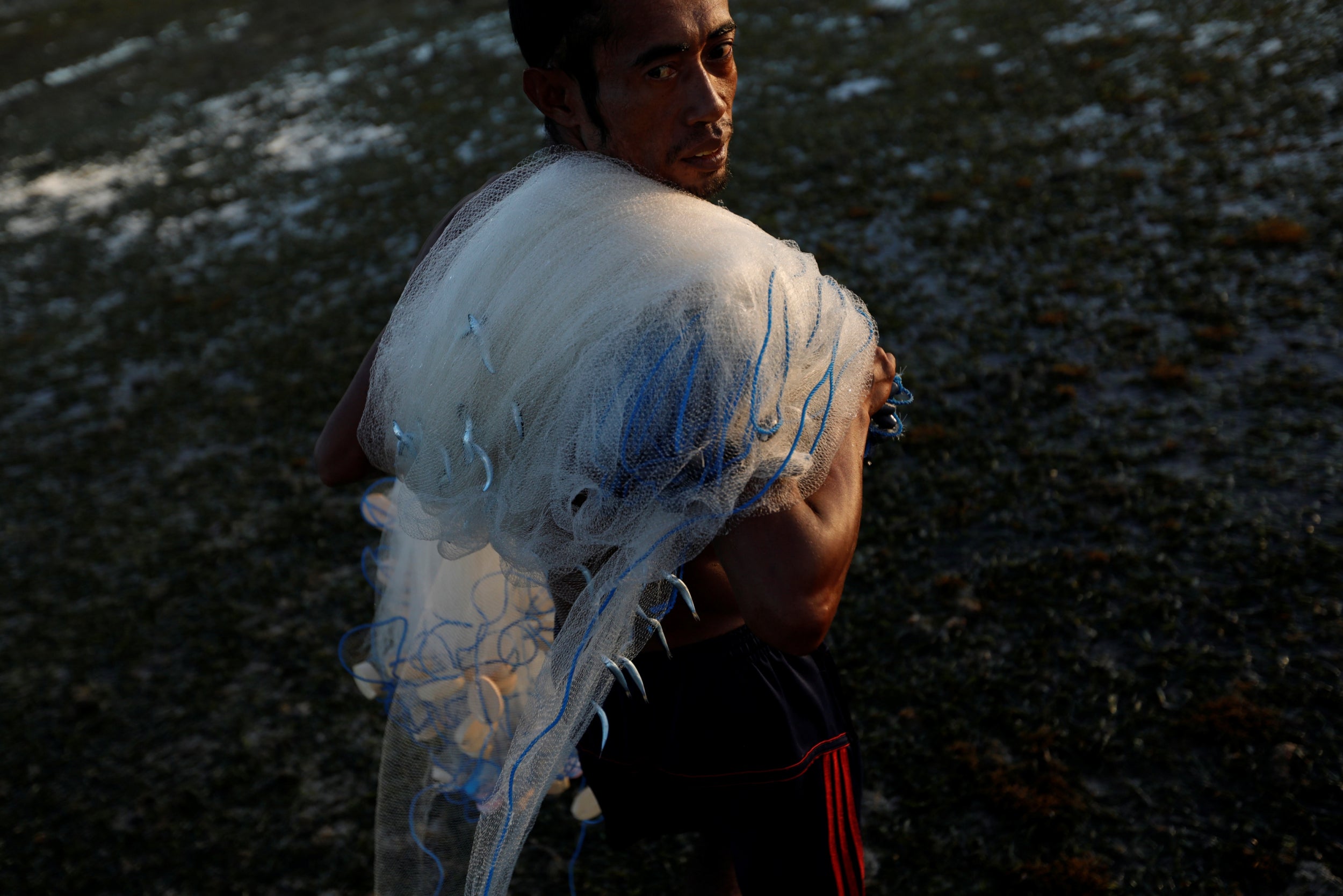 Julkarnaen Mansyur, a fisherman from Waingapu, carries his net back to the shore