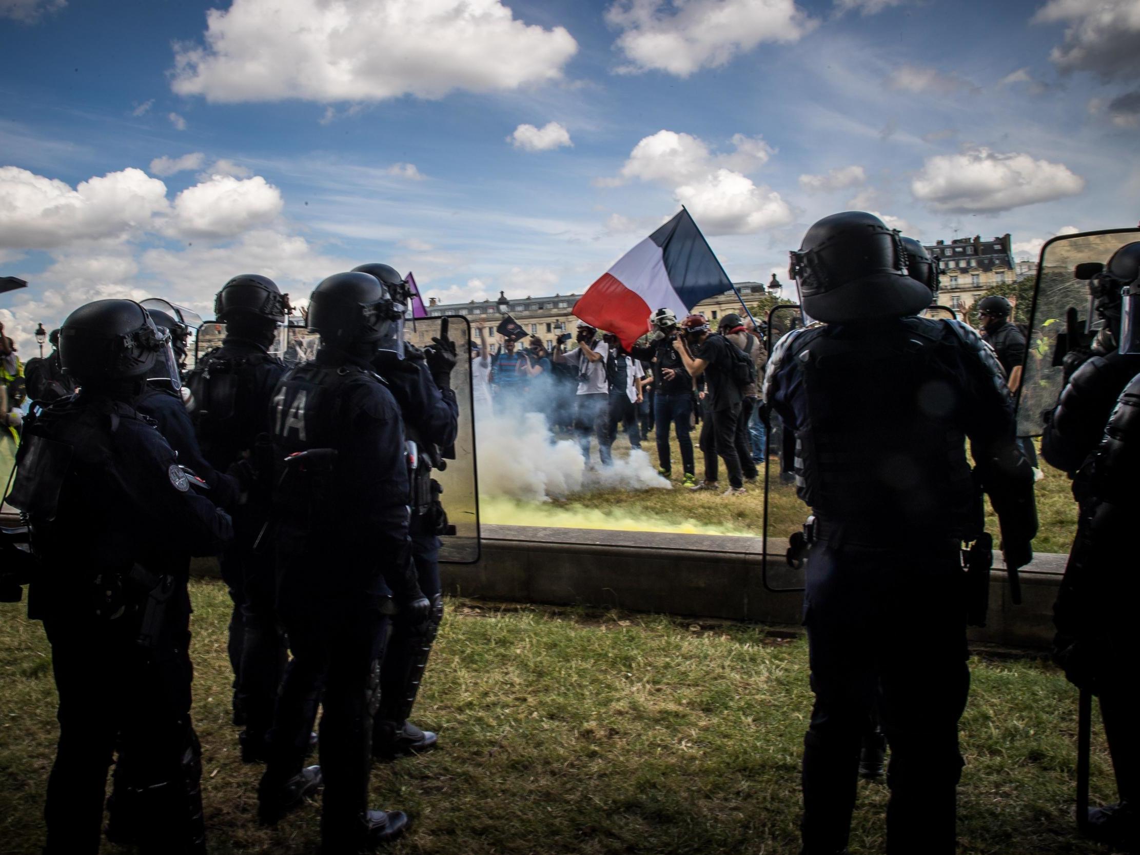 A protester holding a French flag faces police forces during a protest against goverment policies and demand better employment conditions for hospital workers in Paris, France