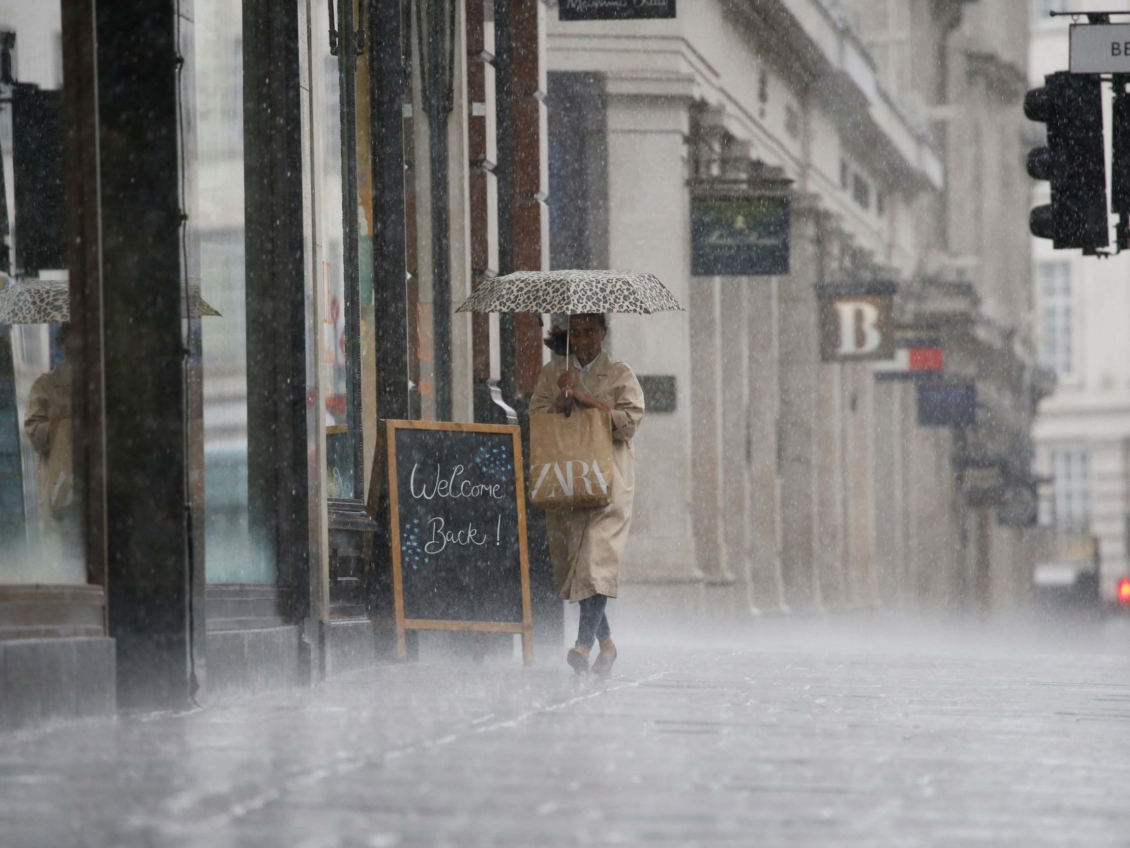 A shopper shelters from the rain as they are caught in a downpour of rain on Oxford Street in London