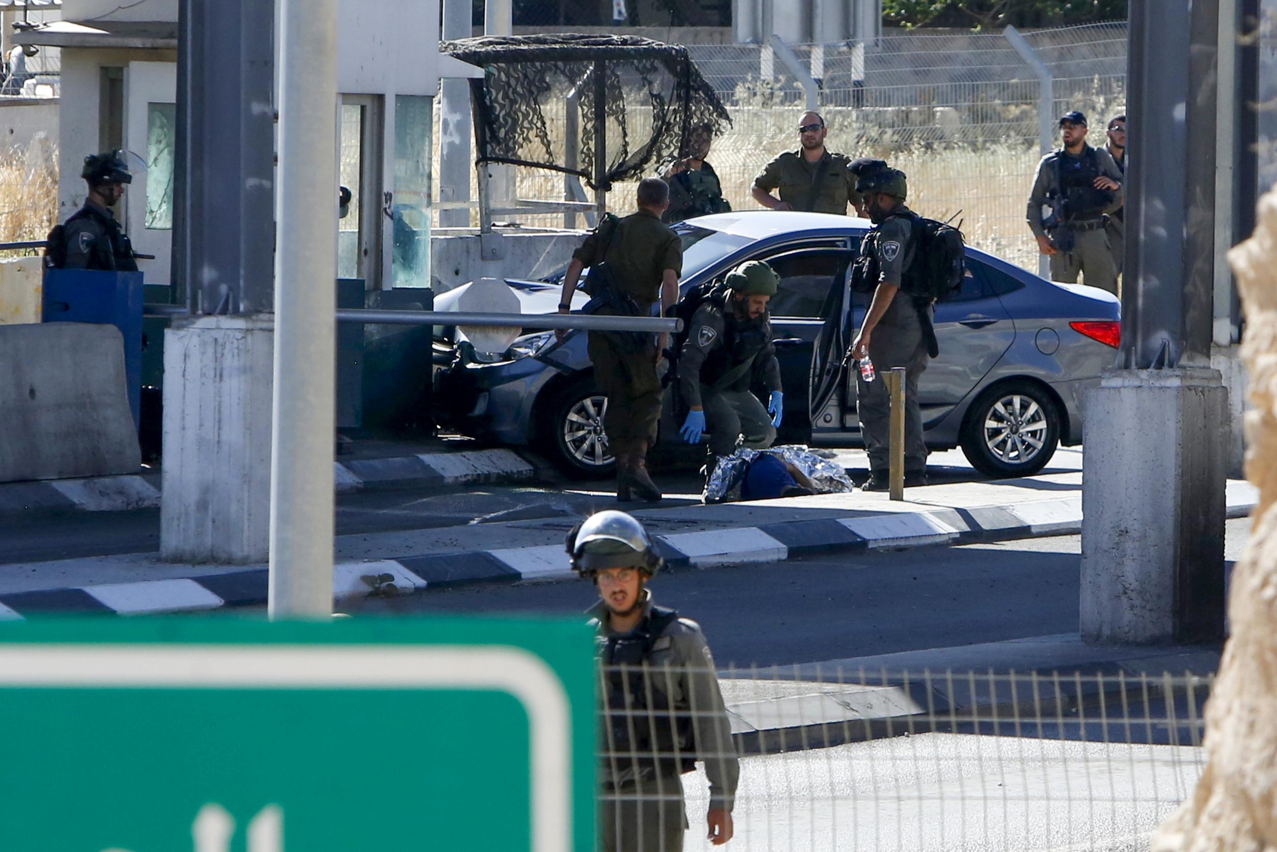 Israeli security forces cover the body of Palestinian Ahmad Erekat, who was shot dead at a checkpoint in the occupied West Bank near the village of Abu Dis