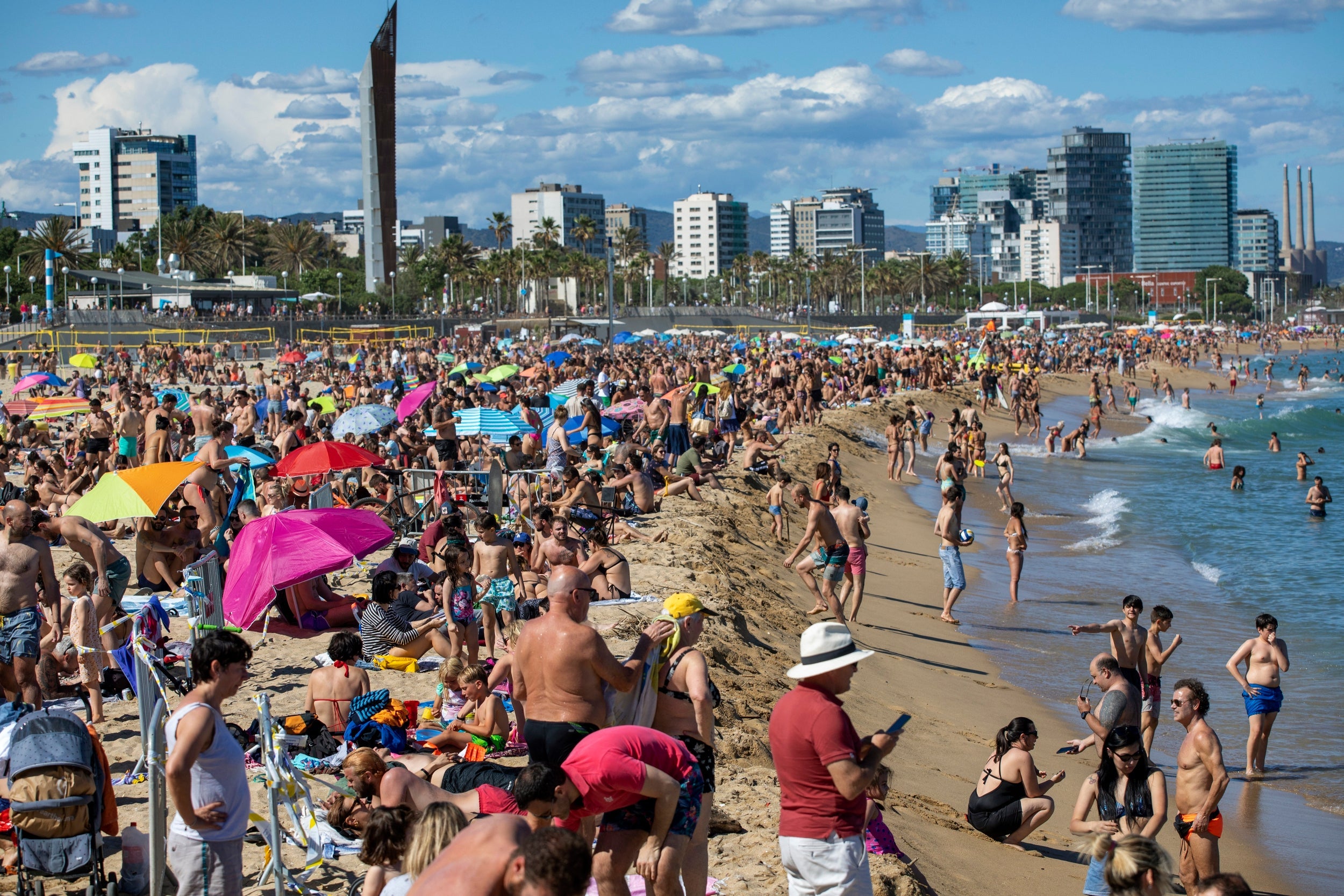 People enjoy the warm weather on the beach in Barcelona, Spain