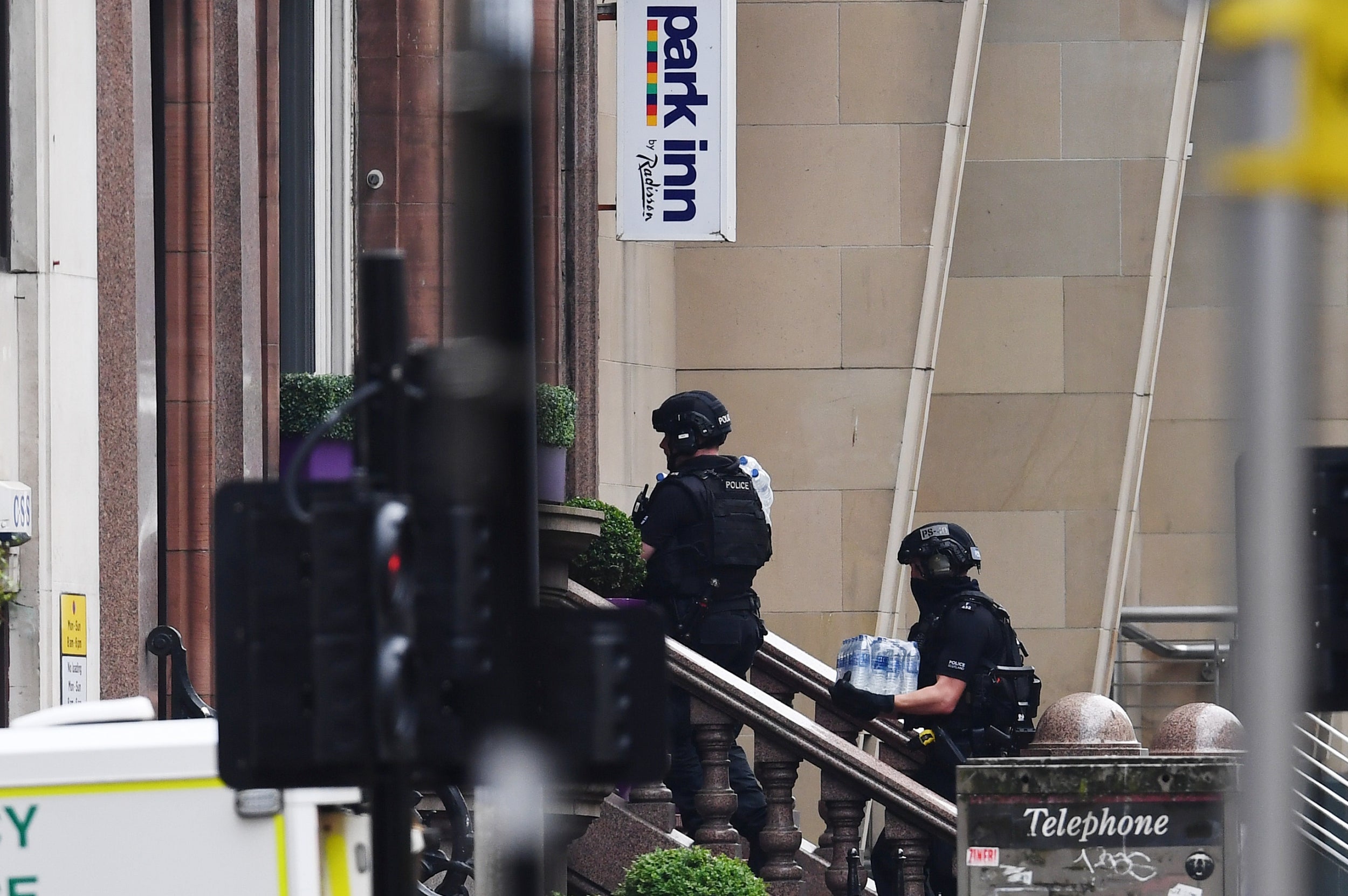 Police officers walk in through the main entrance of the Park Inn Hotel