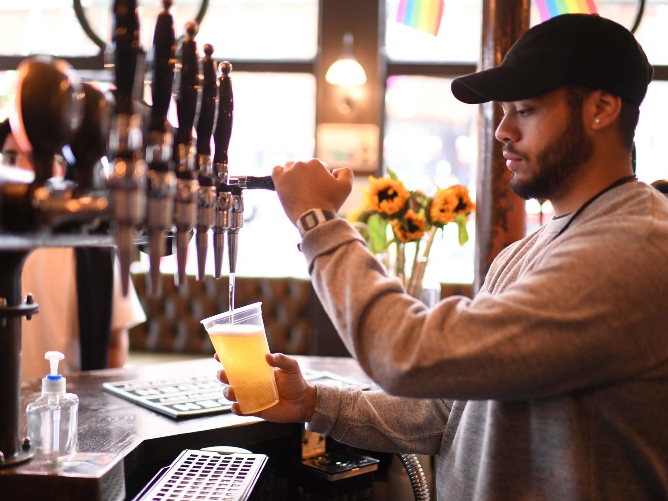 A bartender pours pints for takeaway customers at The Ten Bells pub in east London on June 27, 2020.