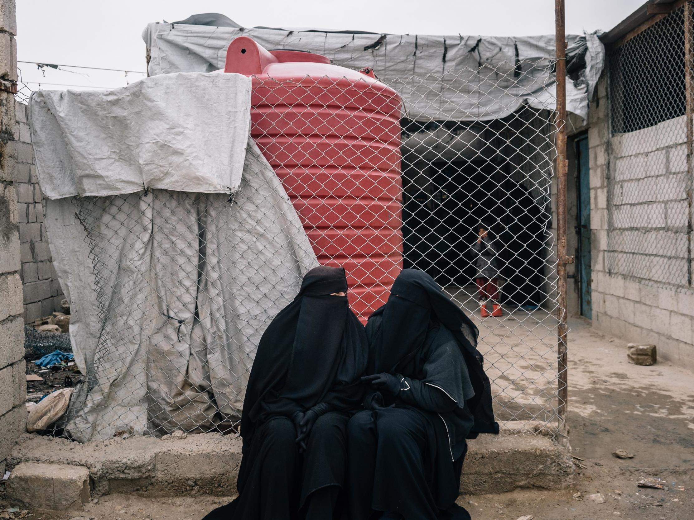 Russian women sit outside a shop in the foreigner's section of al-Hol camp in December 2019