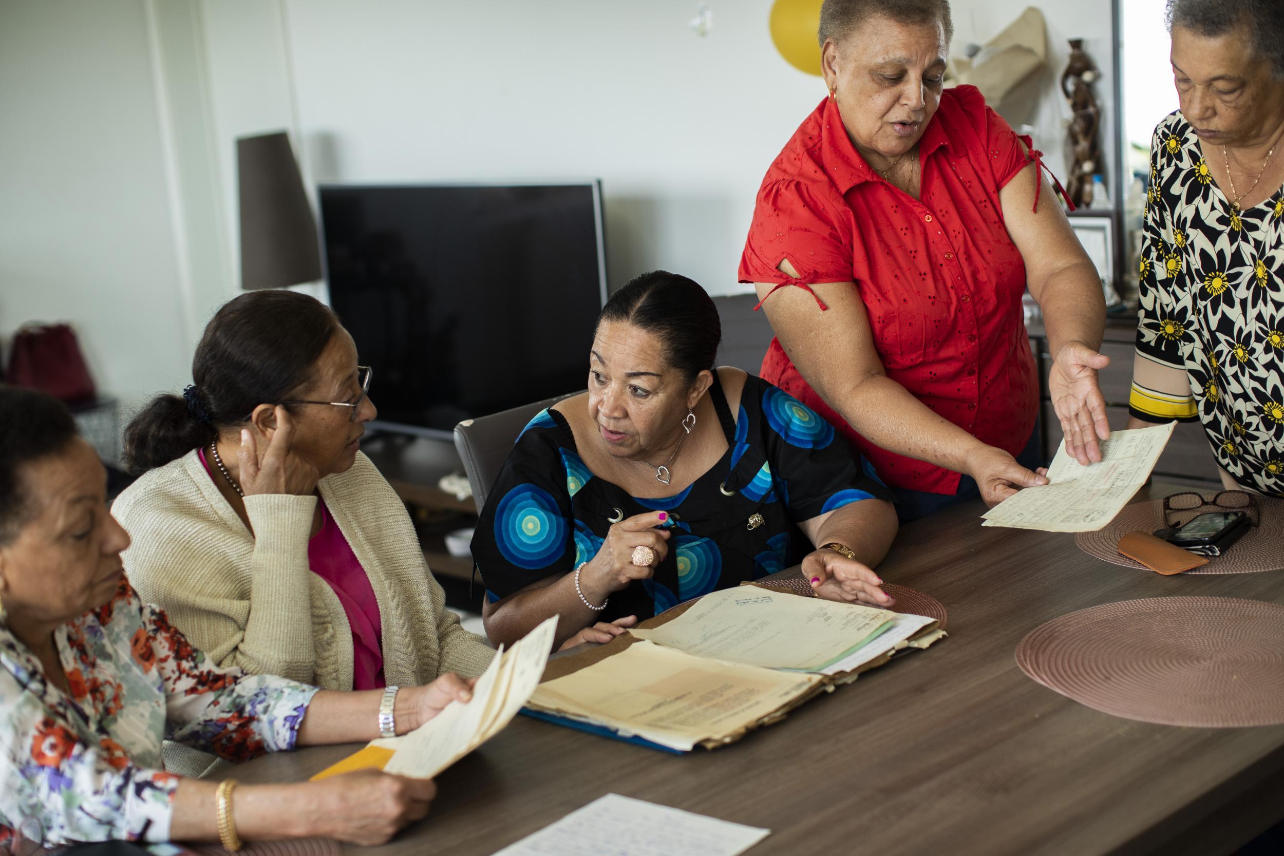 The five women speak with each other as they as they look over their papers during the interview