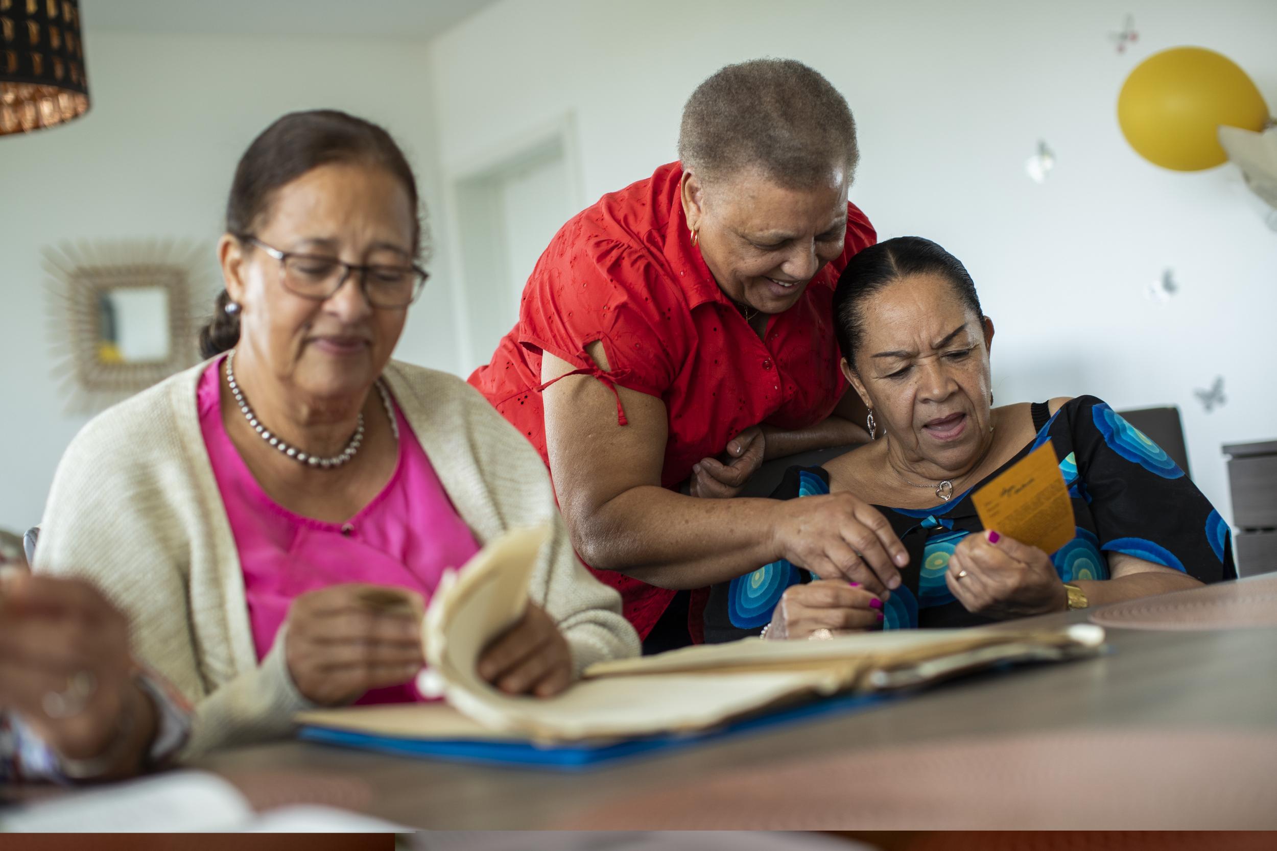 Tavares Mujinga, right, speaks with her friend Ngalula, center, as they look over papers with Bitu Bingi