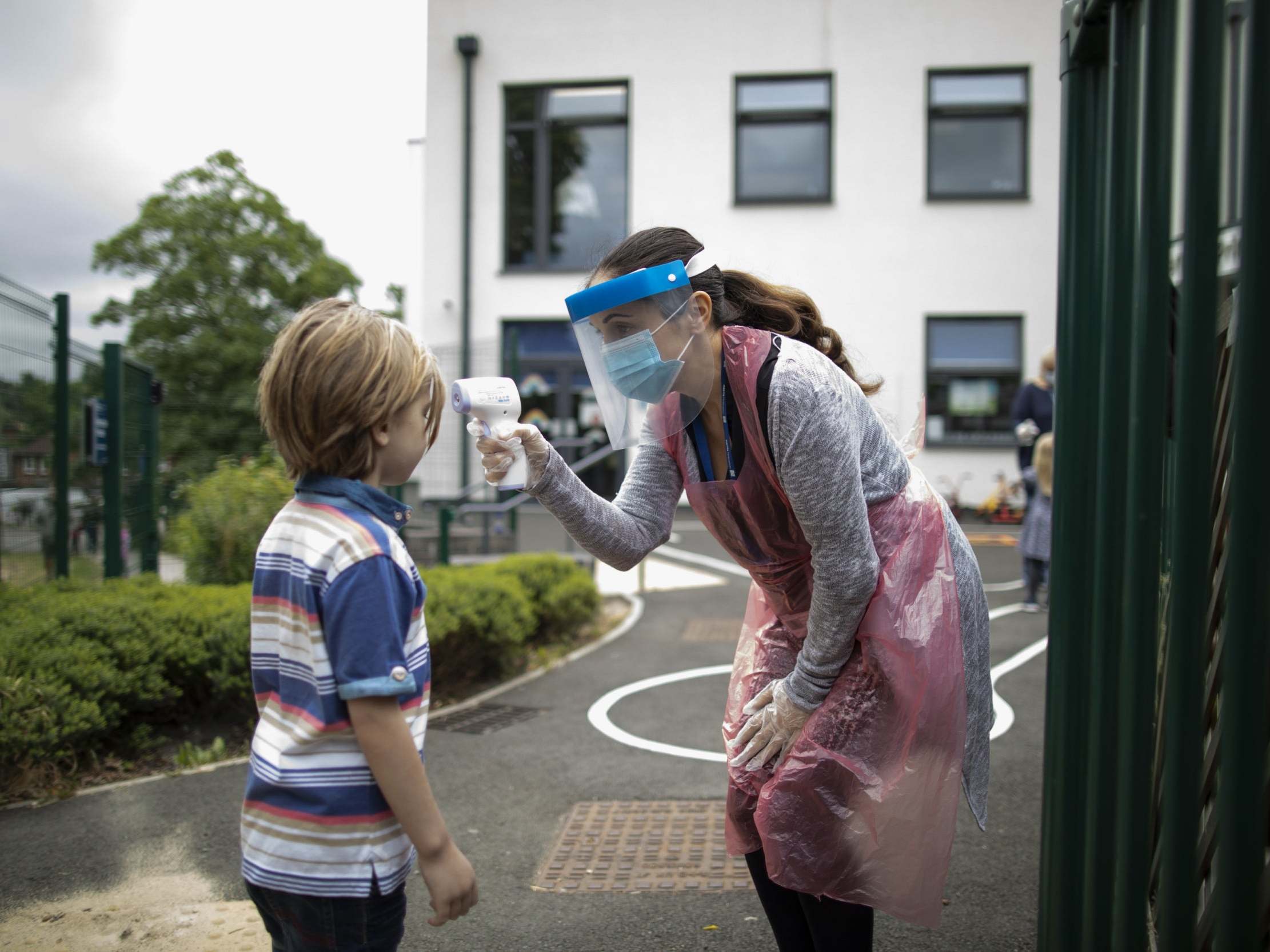 A member of staff wearing personal protective equipment (PPE) takes a child's temperature at the Harris Academy's Shortland's school