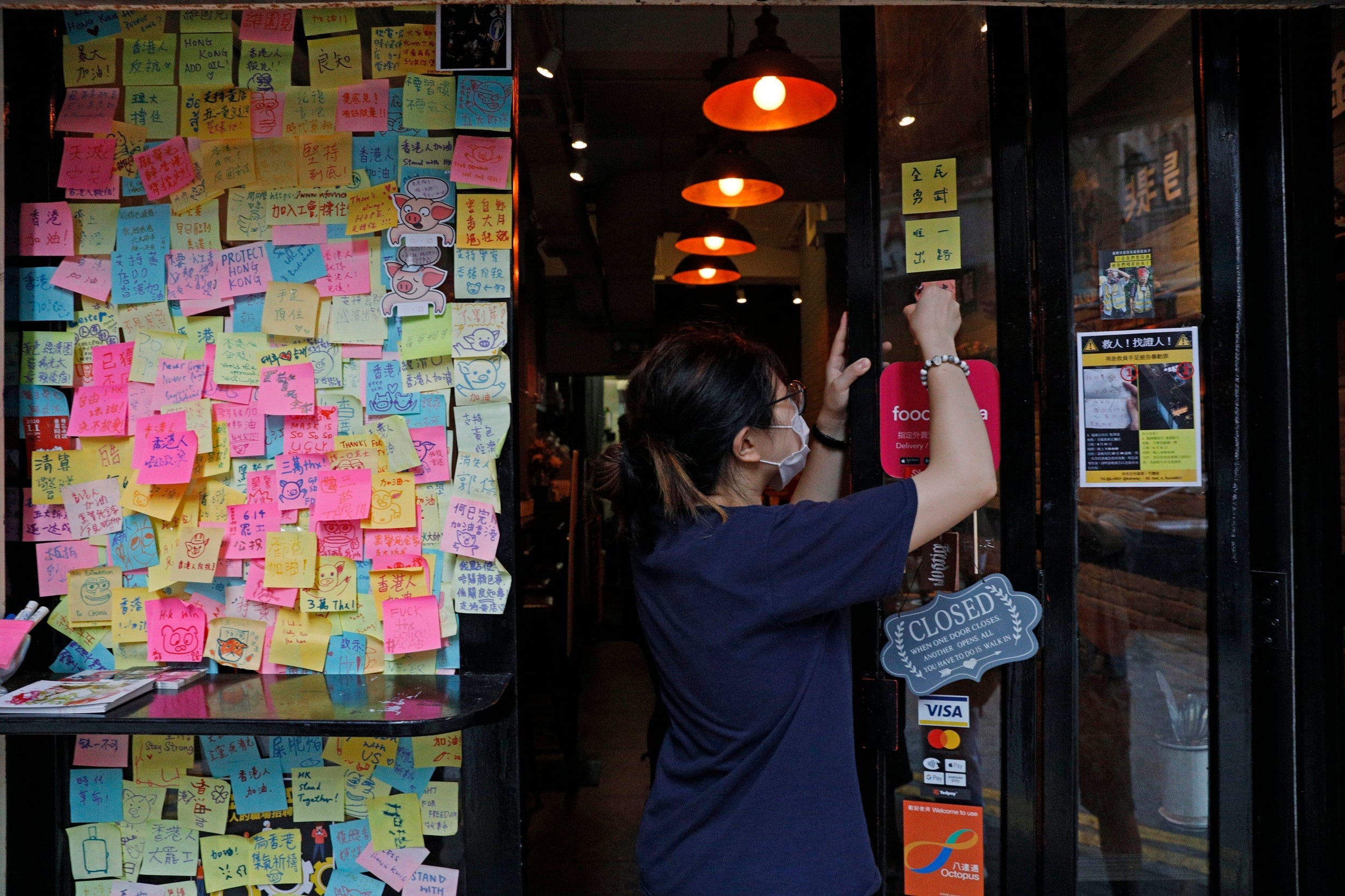 A restaurant employee removes stickers and posters with messages in support of the pro-democracy movement