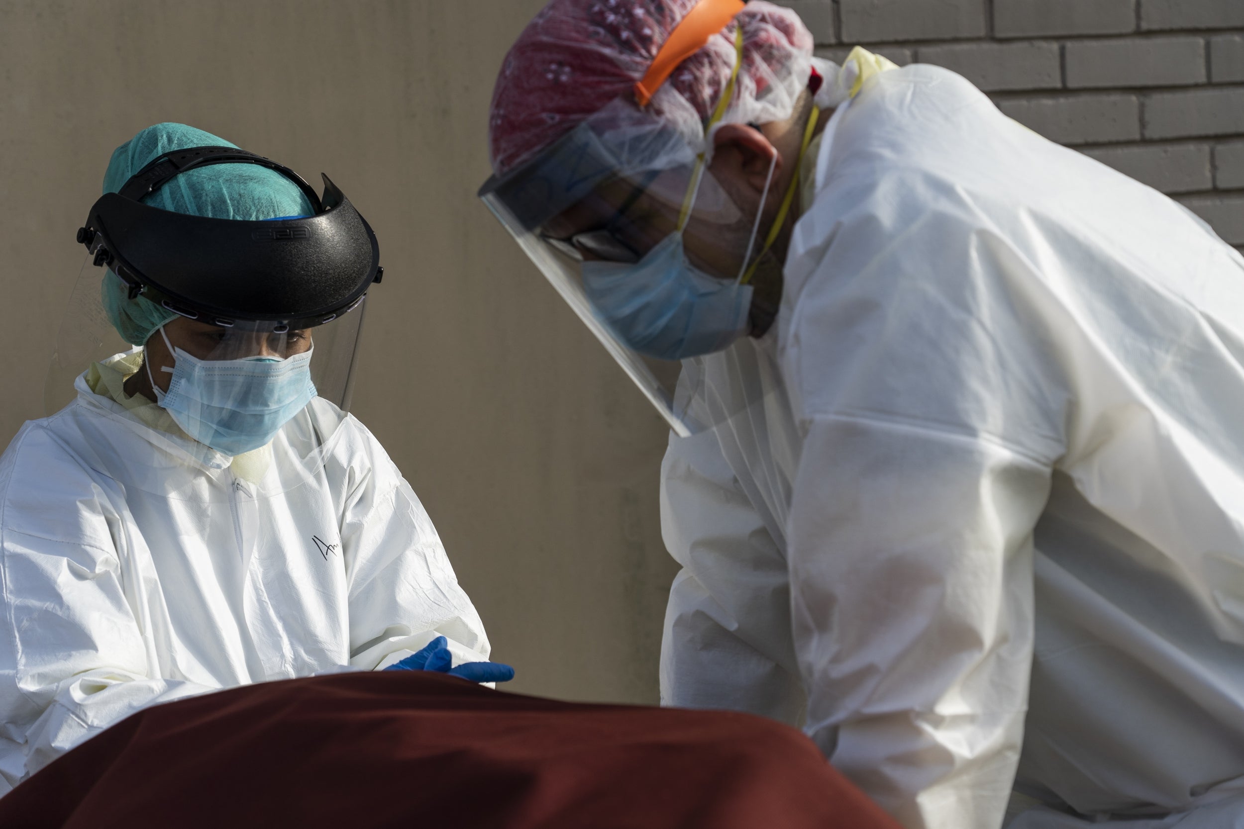 Medical staff wearing full PPE at a hospital in Houston, Texas wait for a car to pick up a body