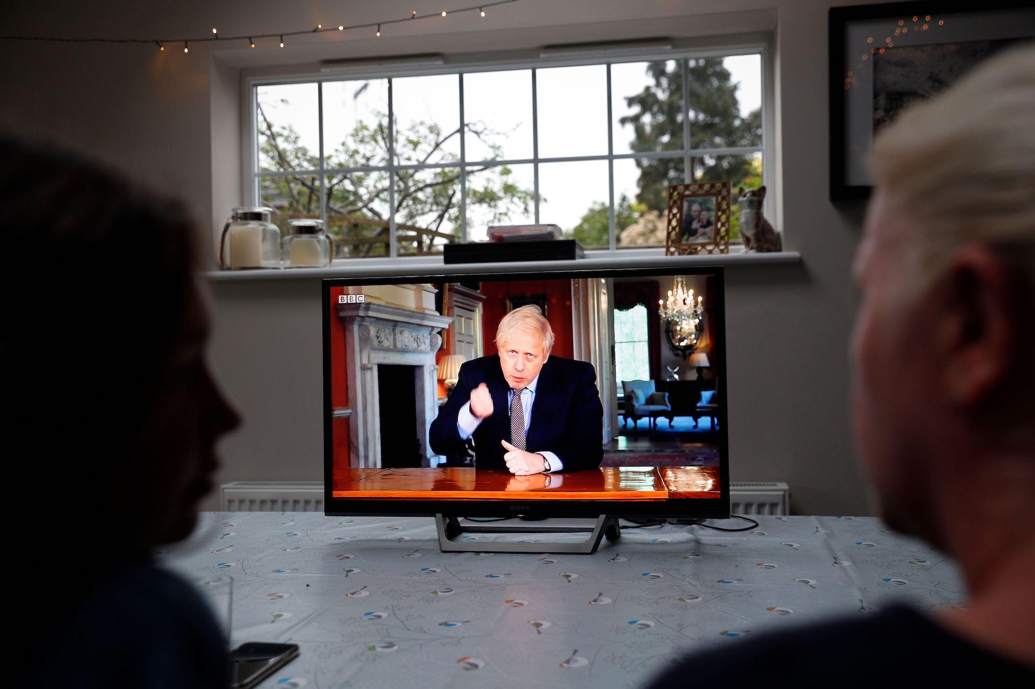 A family gather around the television to watch Britain's Prime Minister Boris Johnson give a televised message to the nation in Hartley Wintney, west of London on May 10, 2020, as the government sets out it's roadmap to ease the national lockdown due to the novel coronavirus COVID-19 pandemic