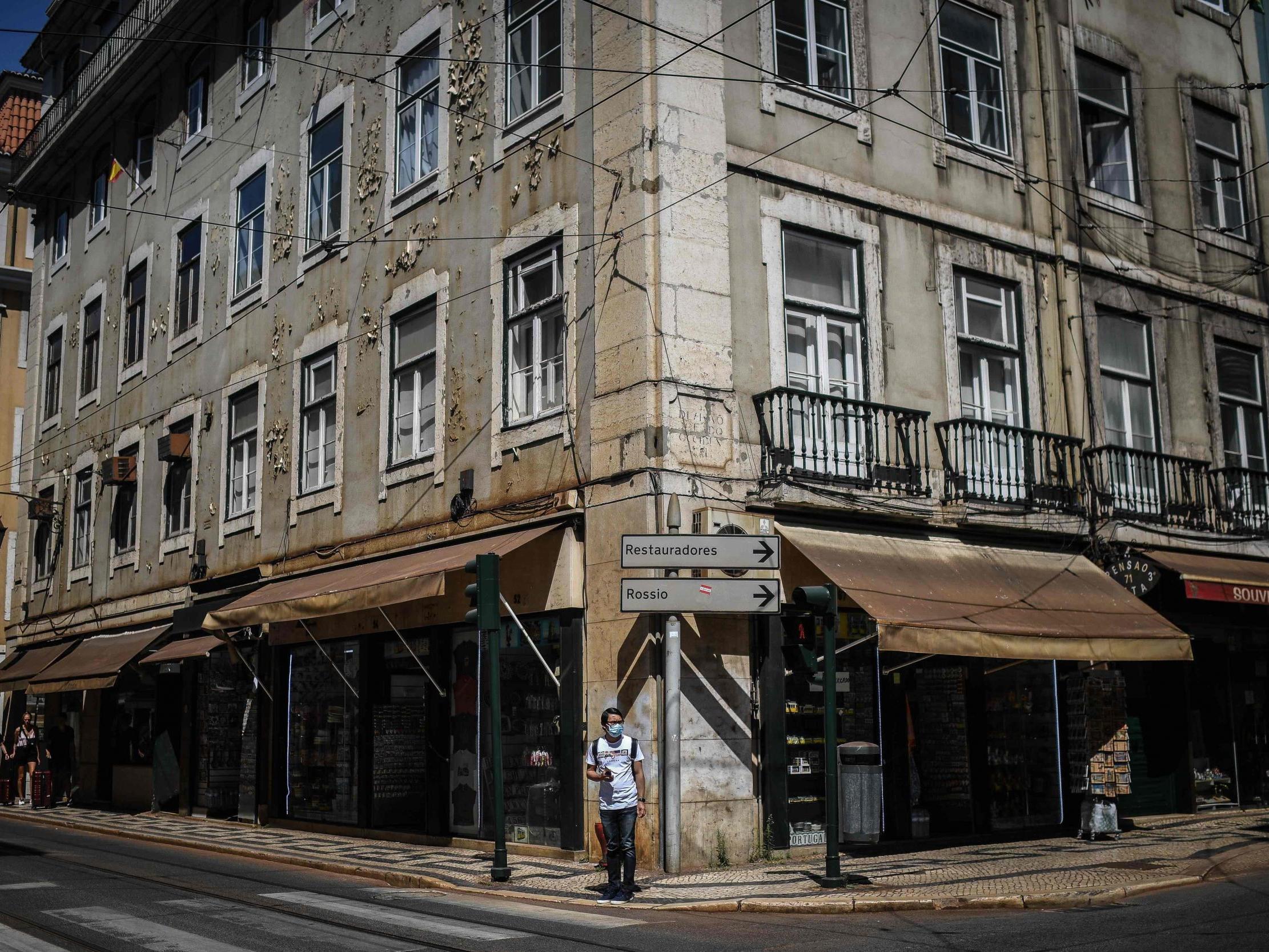 A man in a face mask cross a road in Lisbon on 23 June, 2020.