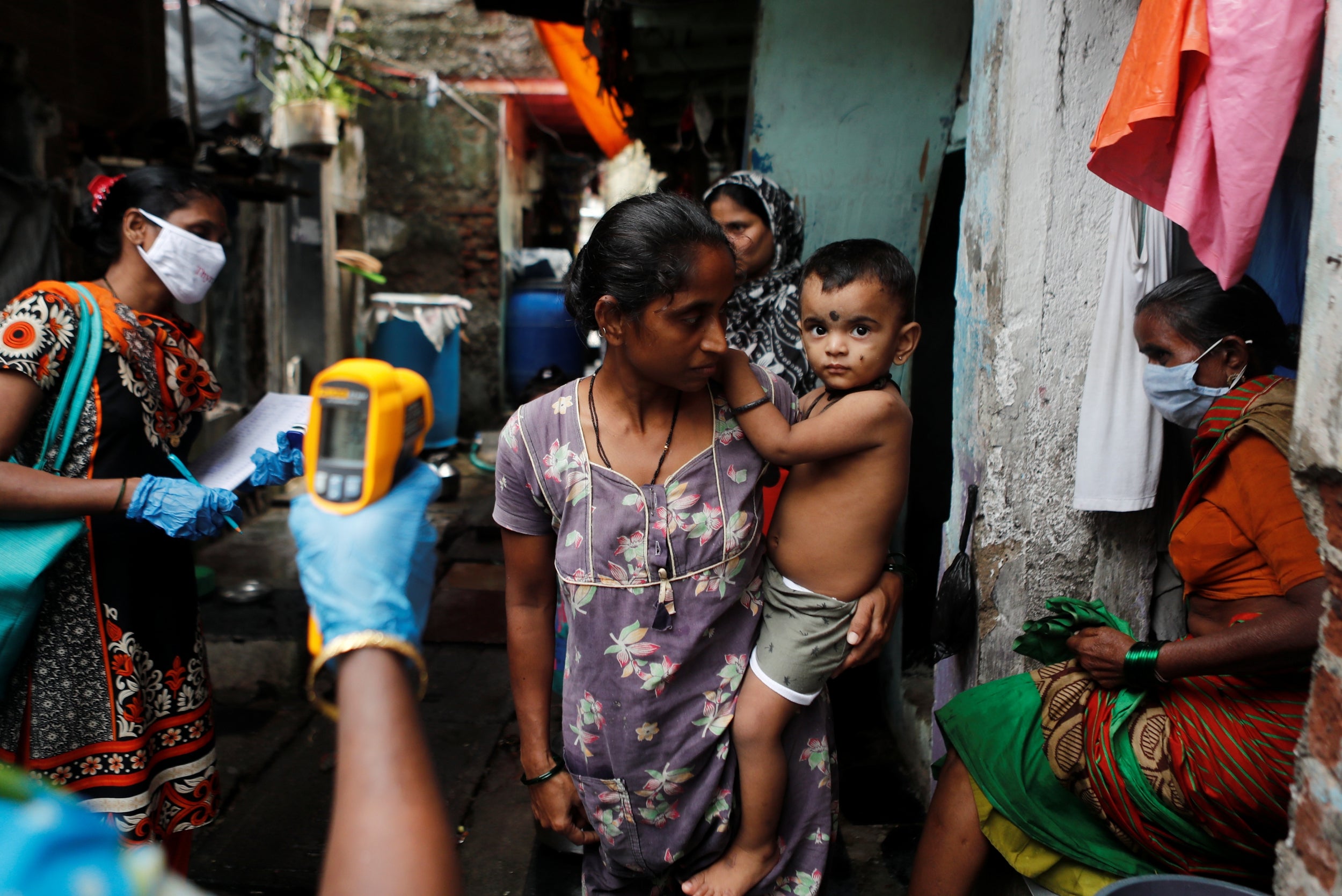 A healthcare worker checks the temperature of residents of a slum area using an electronic thermometer during a check-up campaign for the coronavirus disease (COVID-19), in Mumbai, India