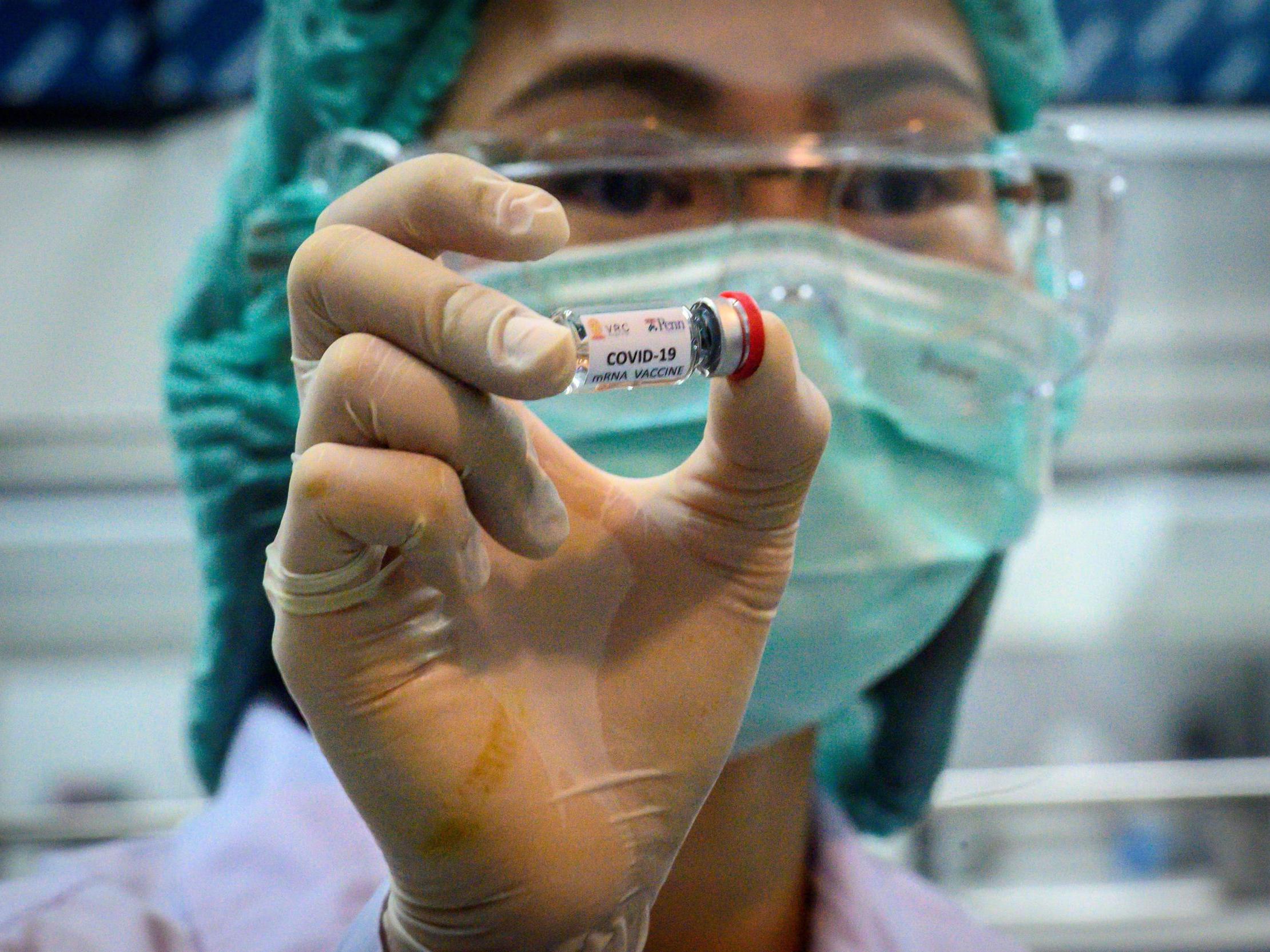This picture taken on 23 May 2020 shows a laboratory technician holding a dose of a Covid-19 novel coronavirus vaccine candidate ready for trial in Thailand