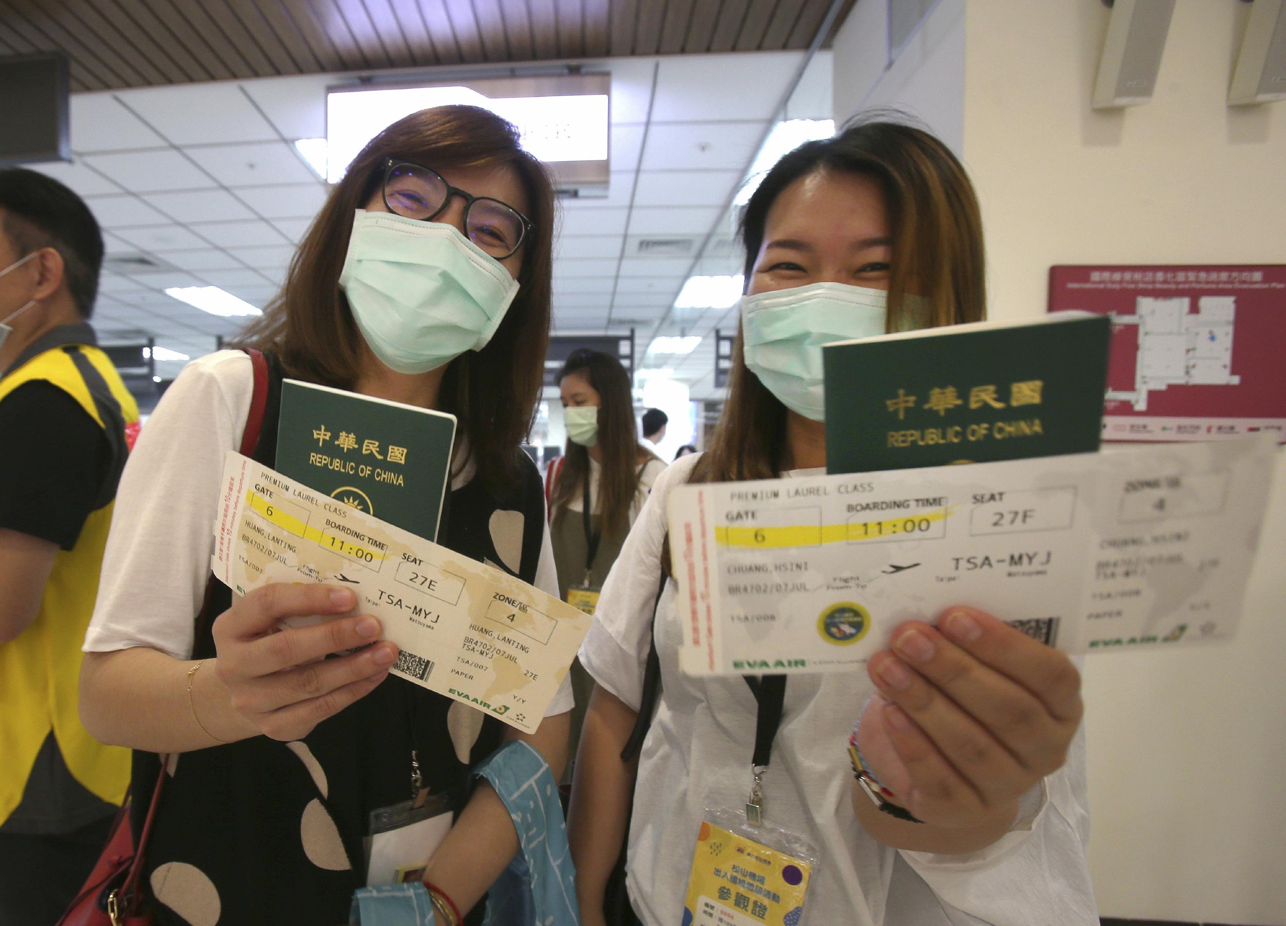 Participants show their boarding pass and passport during a mock trip abroad at Taipei Songshan Airport in Taipei, Taiwan