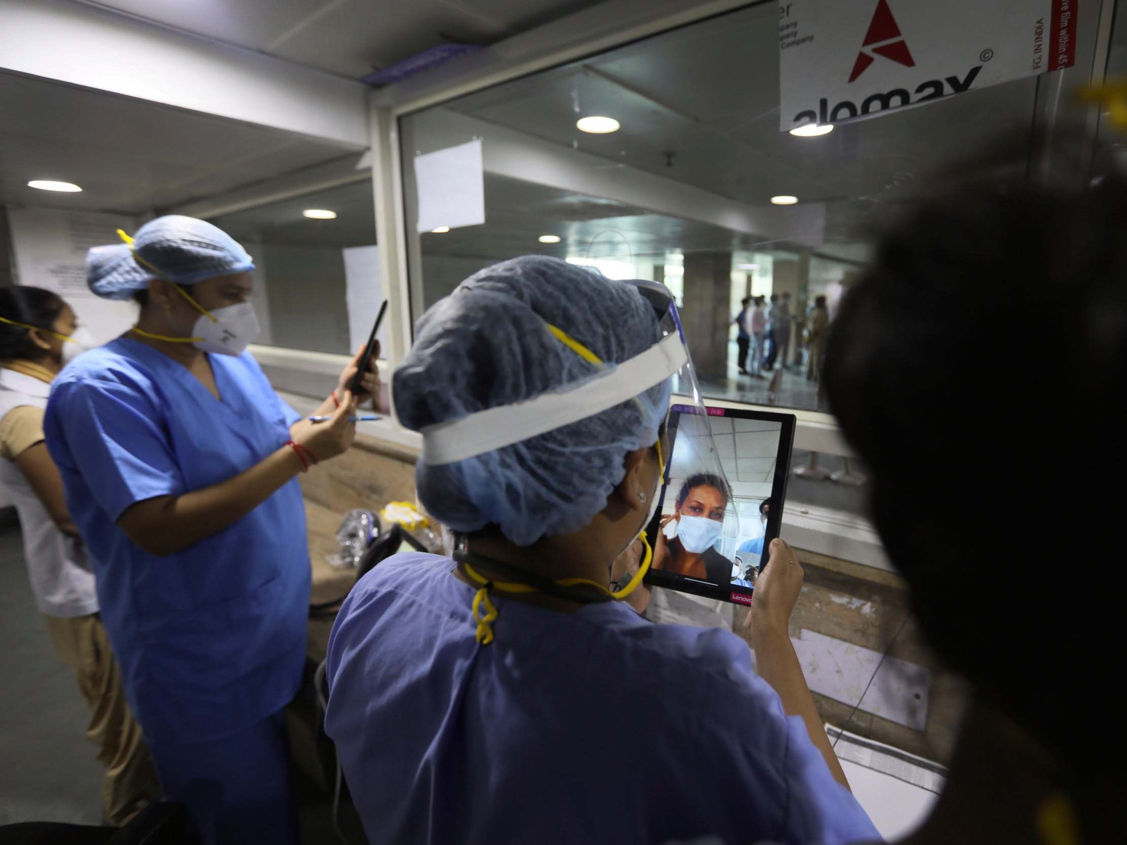 Health workers talk to patients admitted to a Covid-19 hospital through video phones in New Delhi