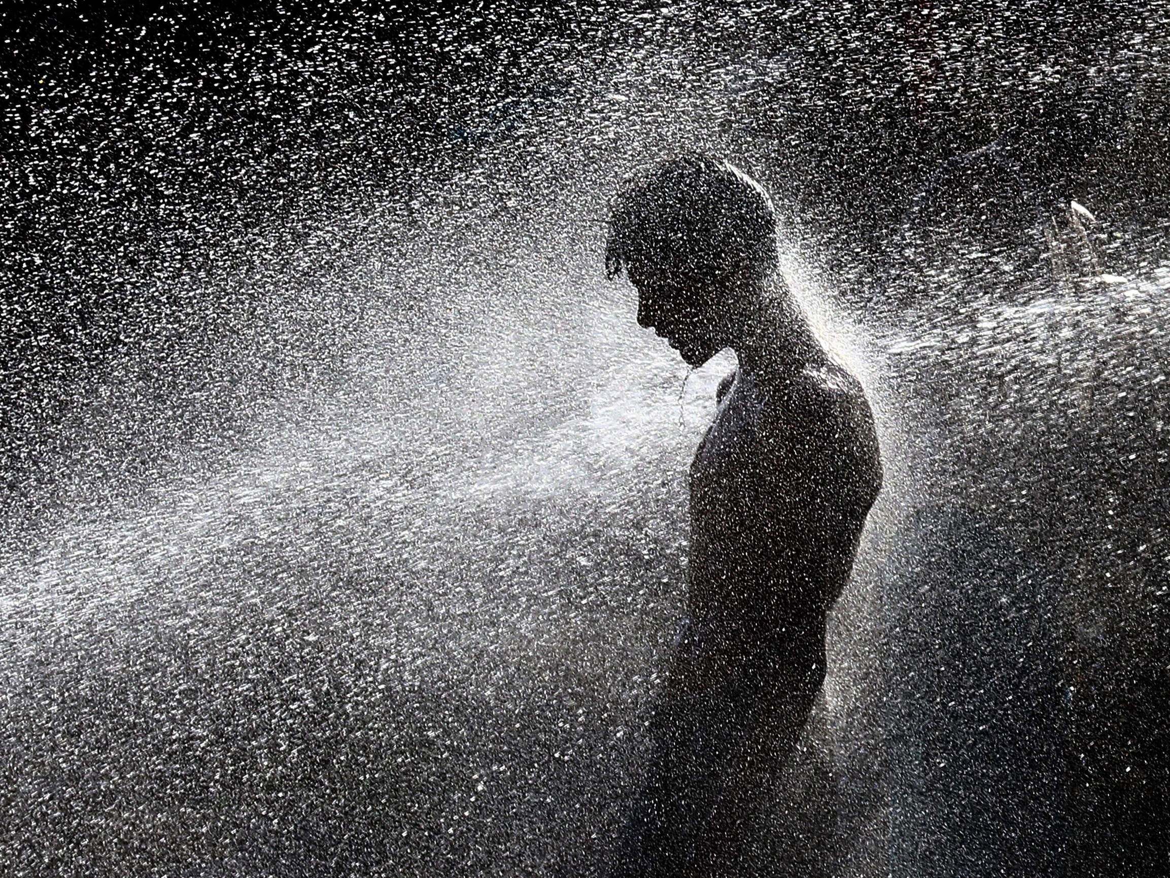 A boy cools off at a punctured water supply line on a road as a heatwave continues in Karachi, Pakistan