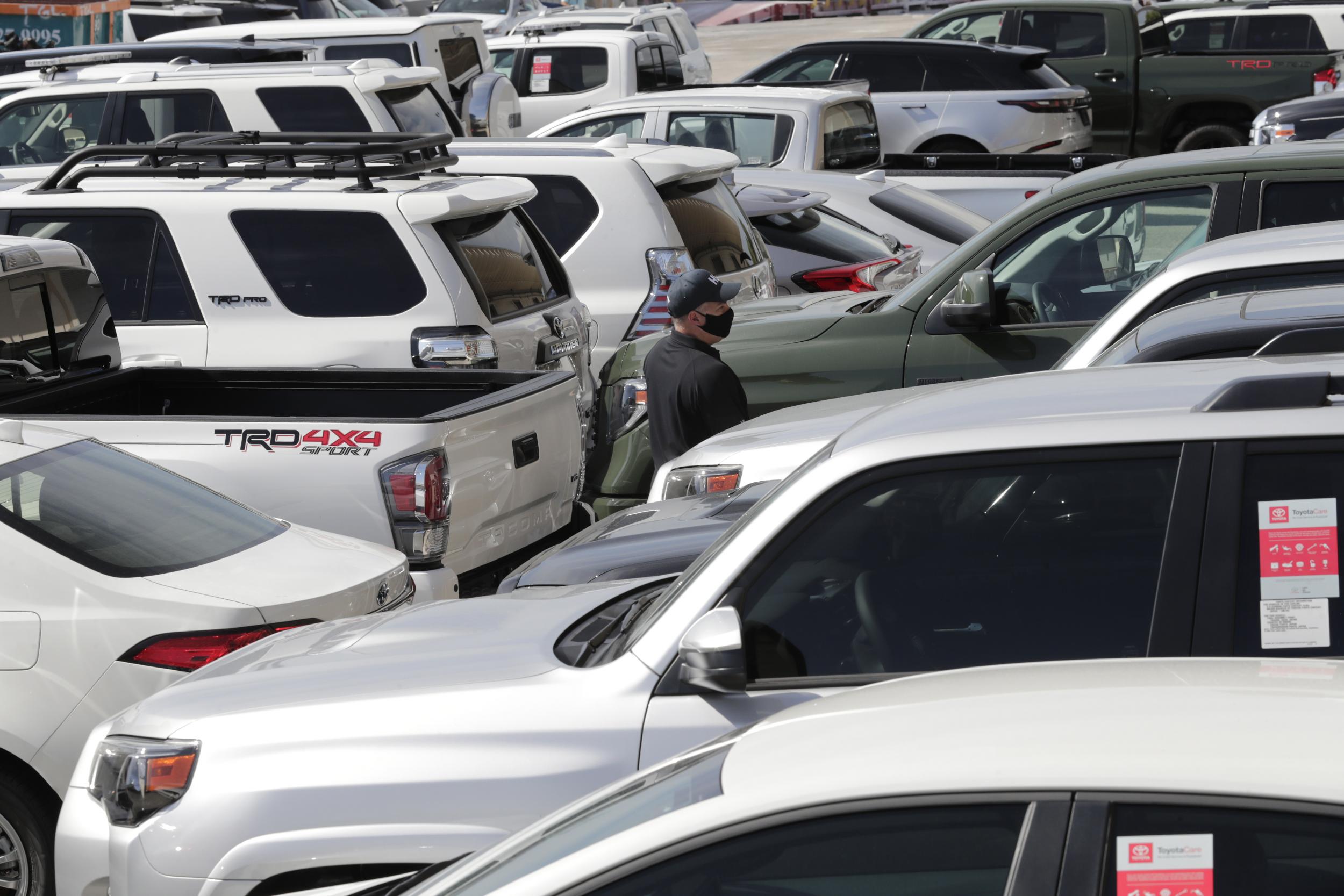 An official with Homeland Security Investigations walks among vehicles worth an estimated $3.2 million, at Port Everglades after they were seized by Homeland Security Investigations, Wednesday, July 8, 2020, in Fort Lauderdale, Fla.