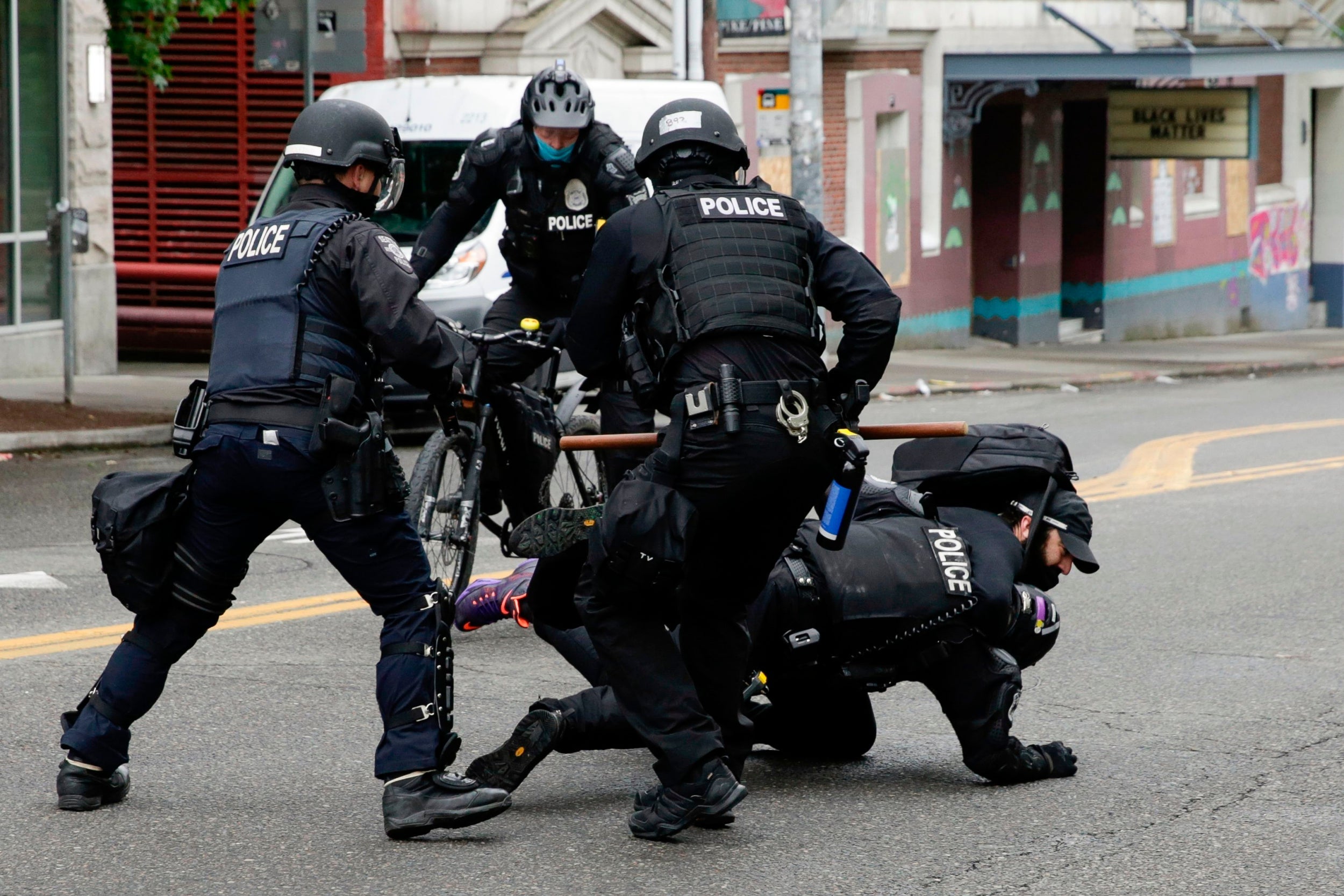 Police officers tackle a demonstrator to the floor at Seattle's CHOP zone, where Independent reporter Andrew Buncombe was arrested