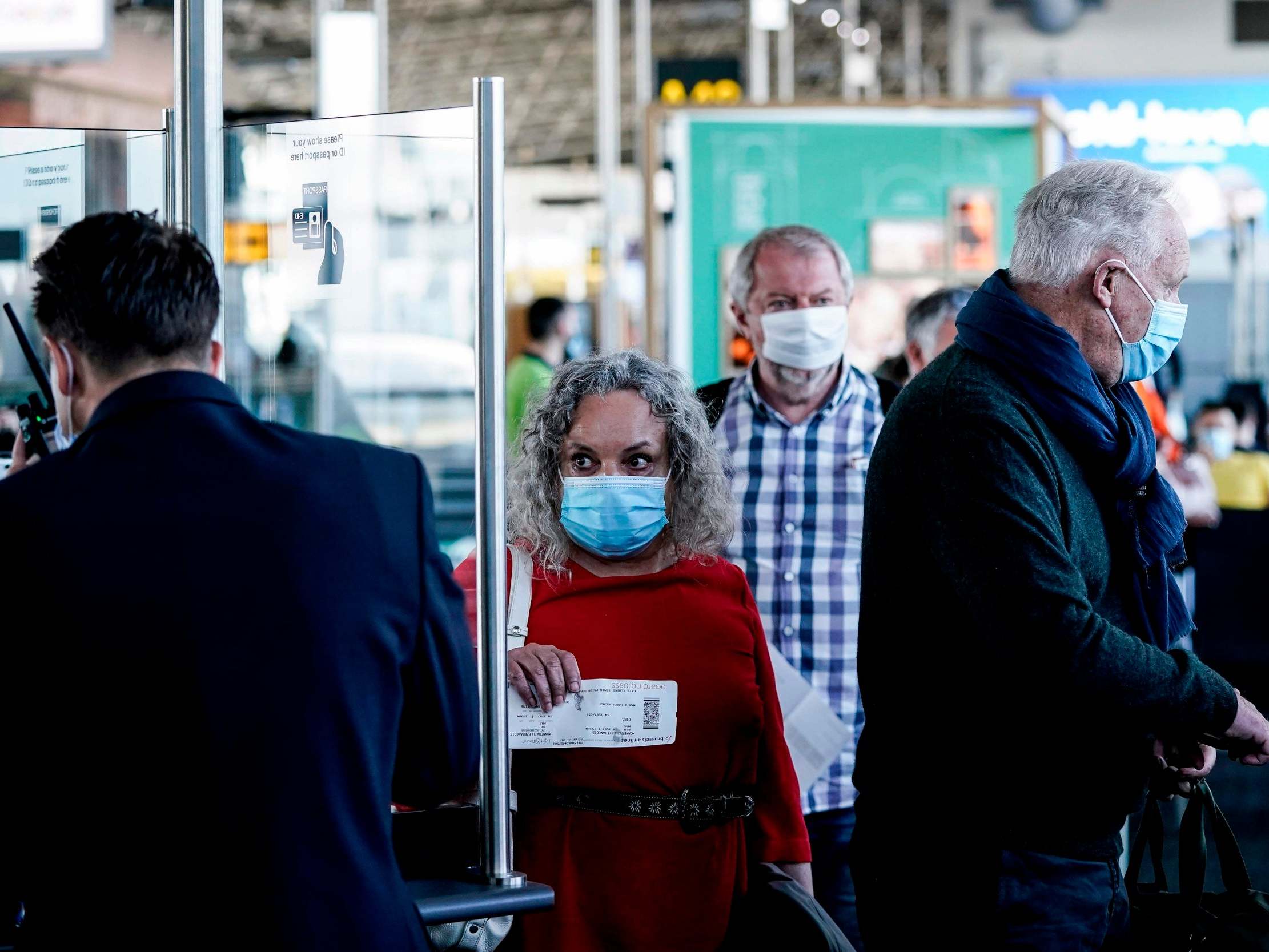 Passengers wearing protective face masks queue at the boarding gate at Brussels Airport, in Zaventem.