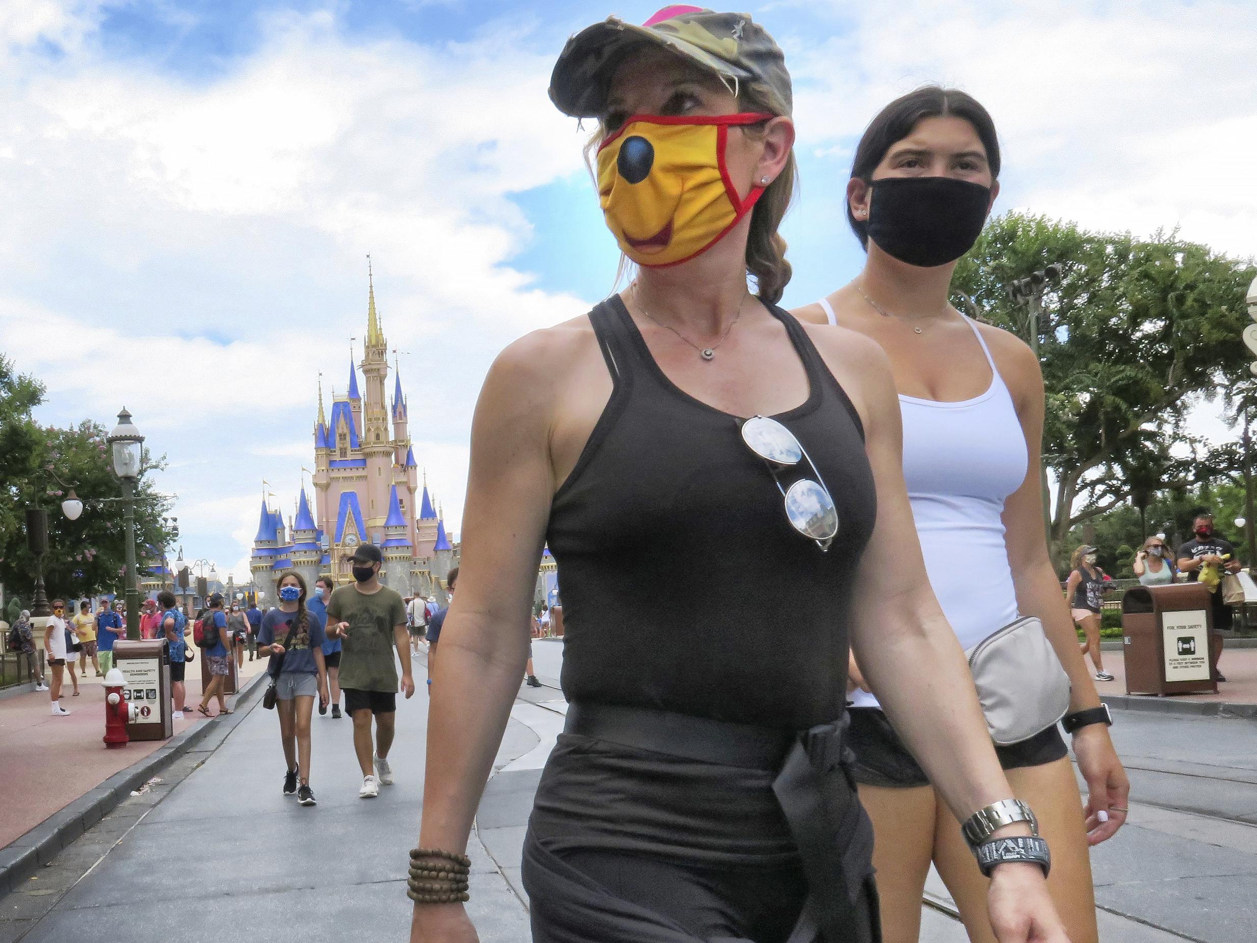 Guests wear masks as required to attend the official reopening day of the Magic Kingdom at Walt Disney World in Lake Buena Vista, Florida