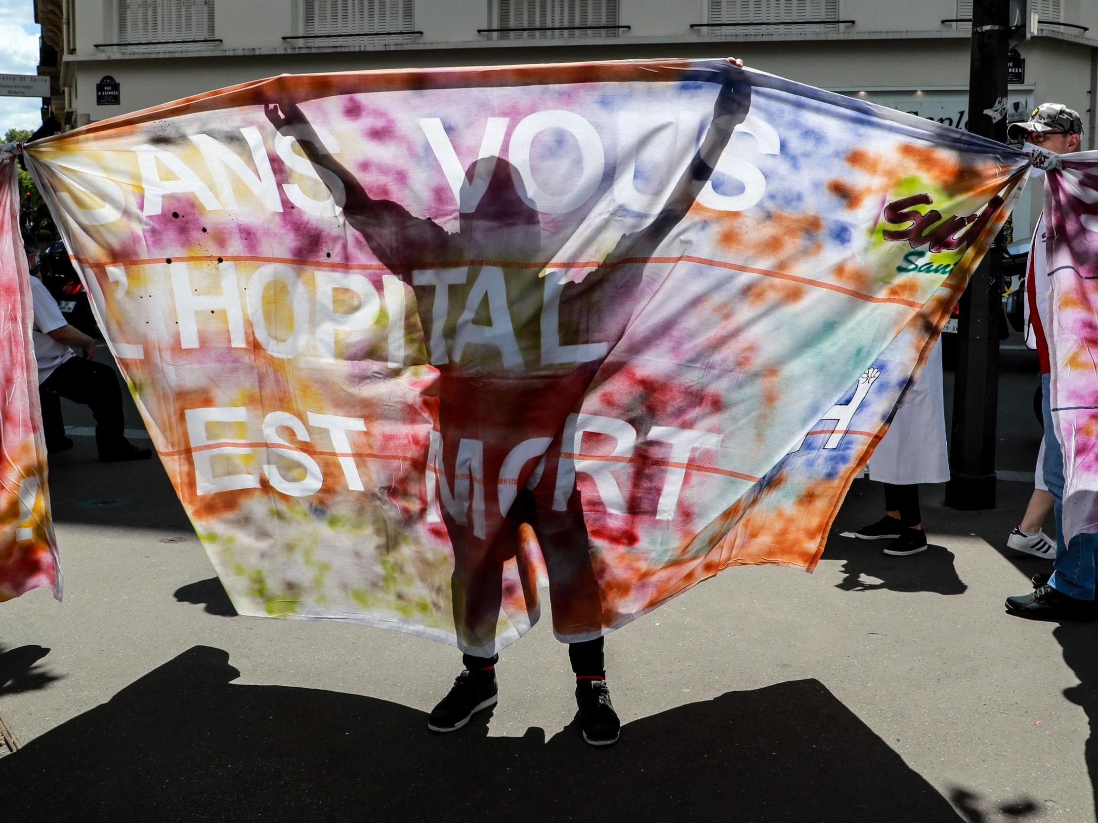 Health workers and trade unions representatives hold a banner reading 'without you, hospital is dead' during a demonstration next to the Health Ministry in Paris