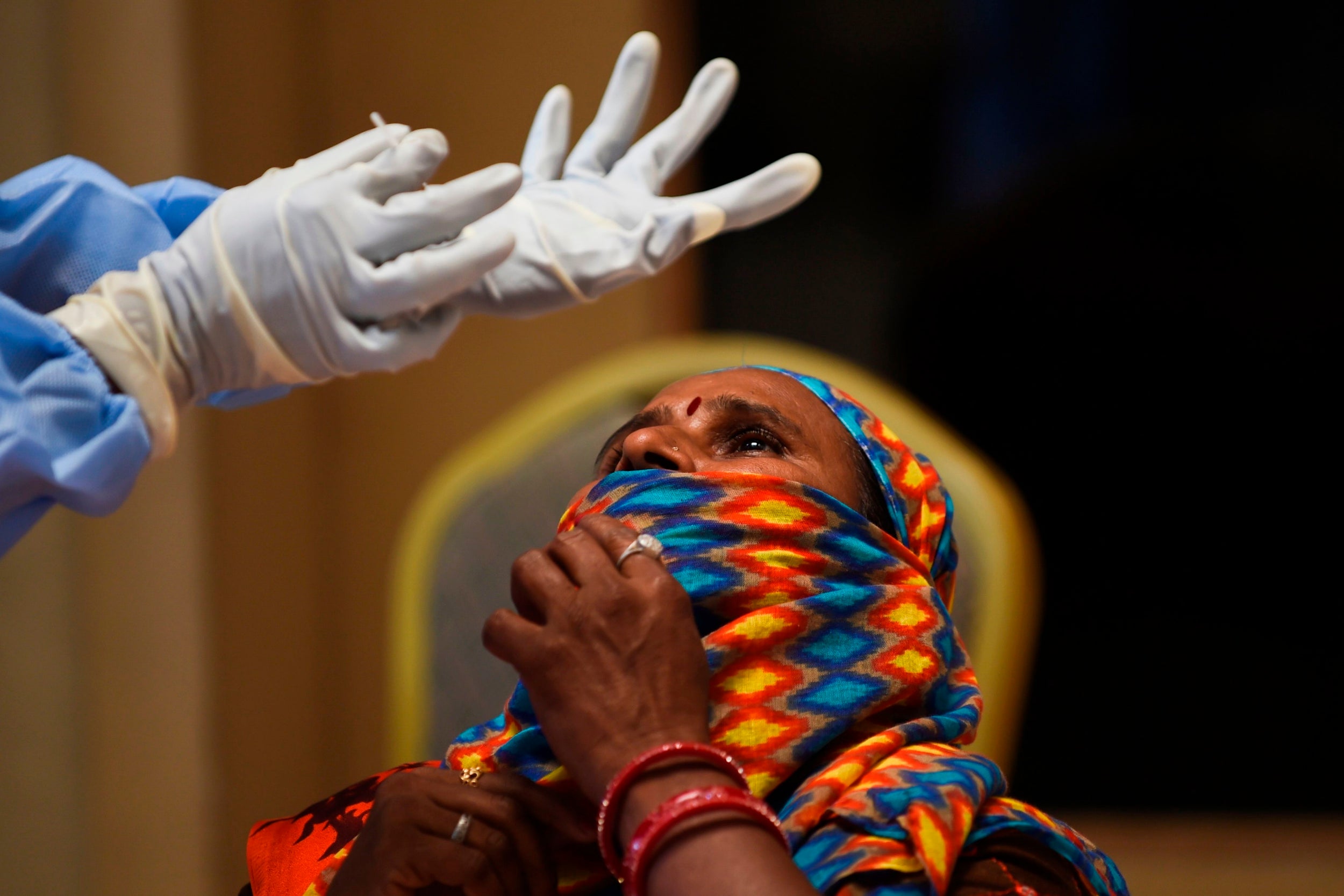 A health worker prepares a rapid coronavirus test at a bus stop in Ahmedabad, India