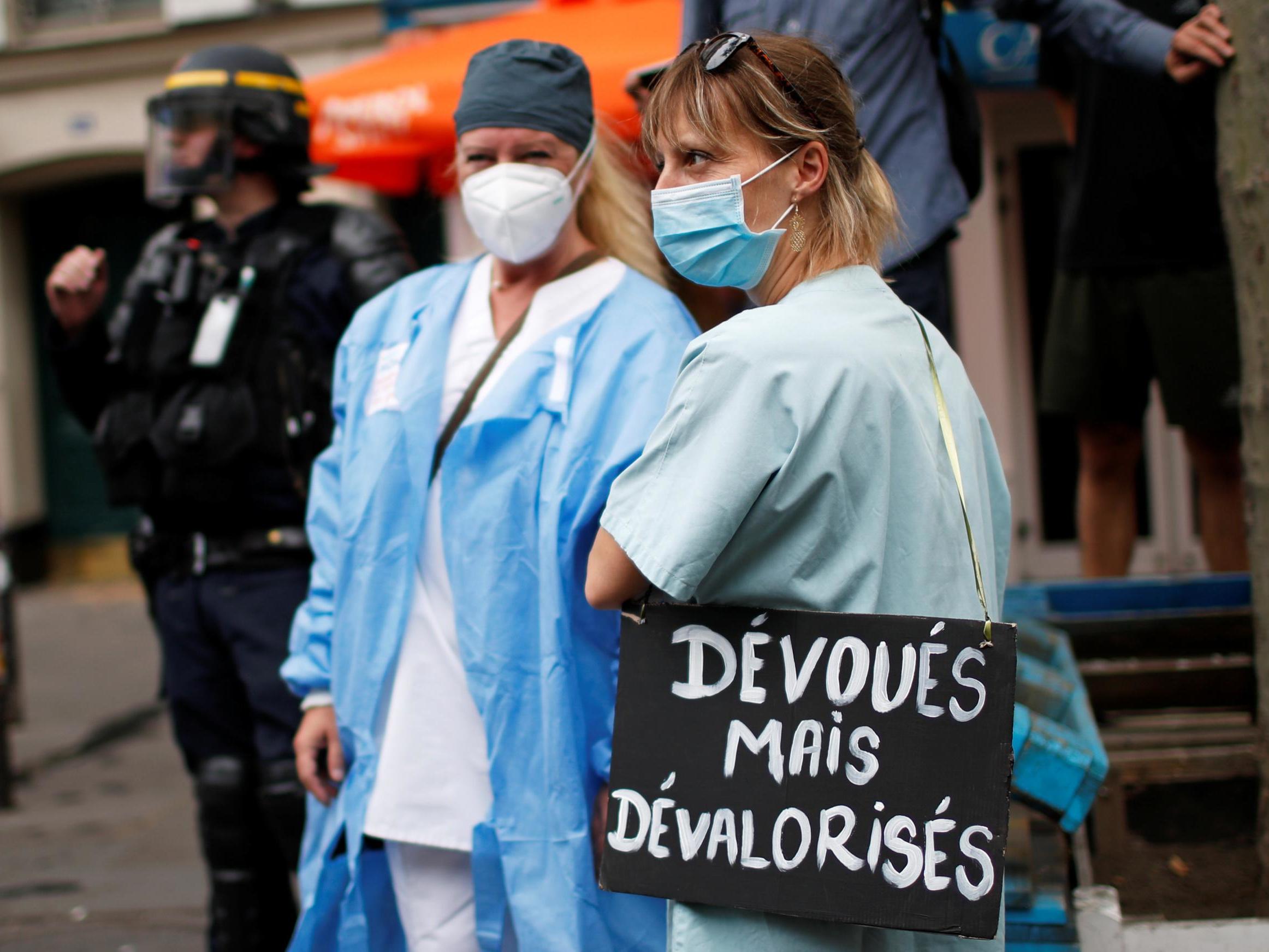 French health workers attend a demonstration on the Bastille Day in Paris, with a sign saying: “Devoted, but underappreciated.” ( REUTERS/Gonzalo Fuentes)