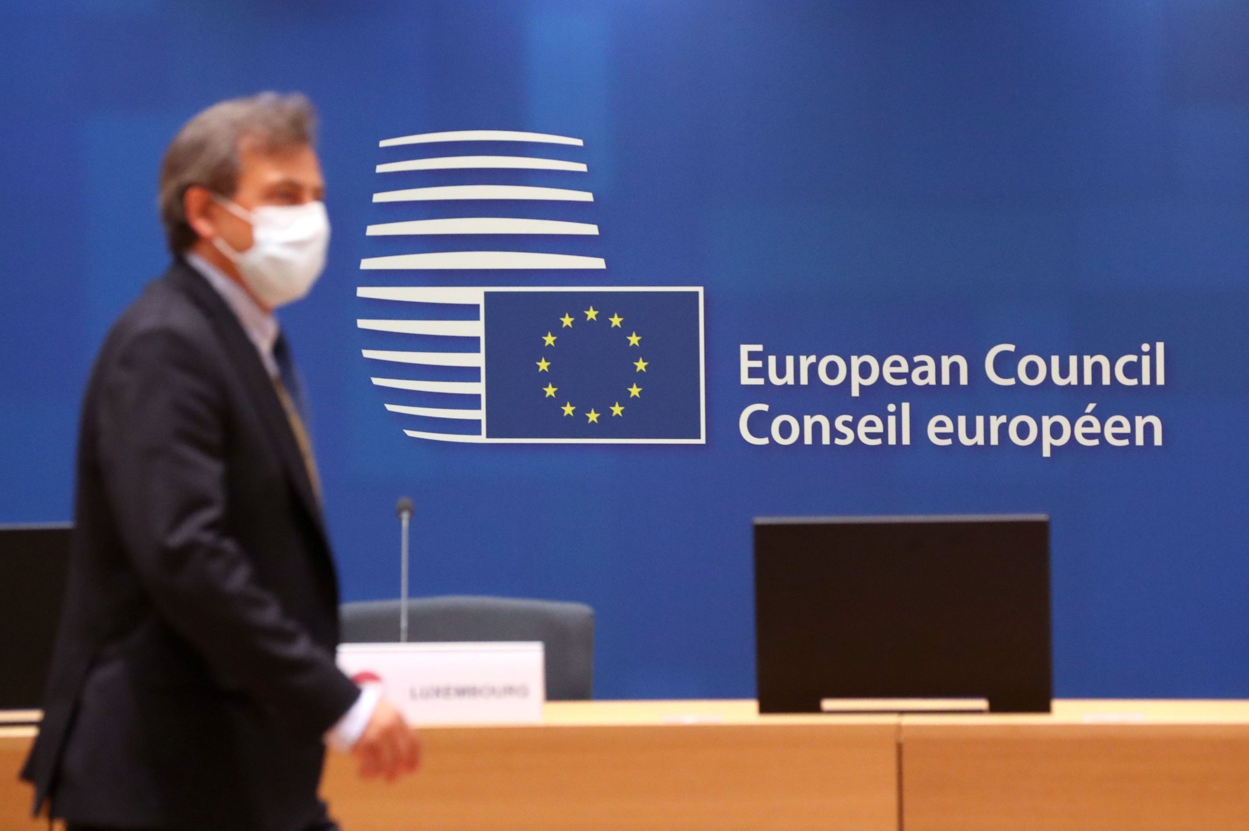 A worker wearing a protective face mask walks through the conference room where an EU leaders summit will take place