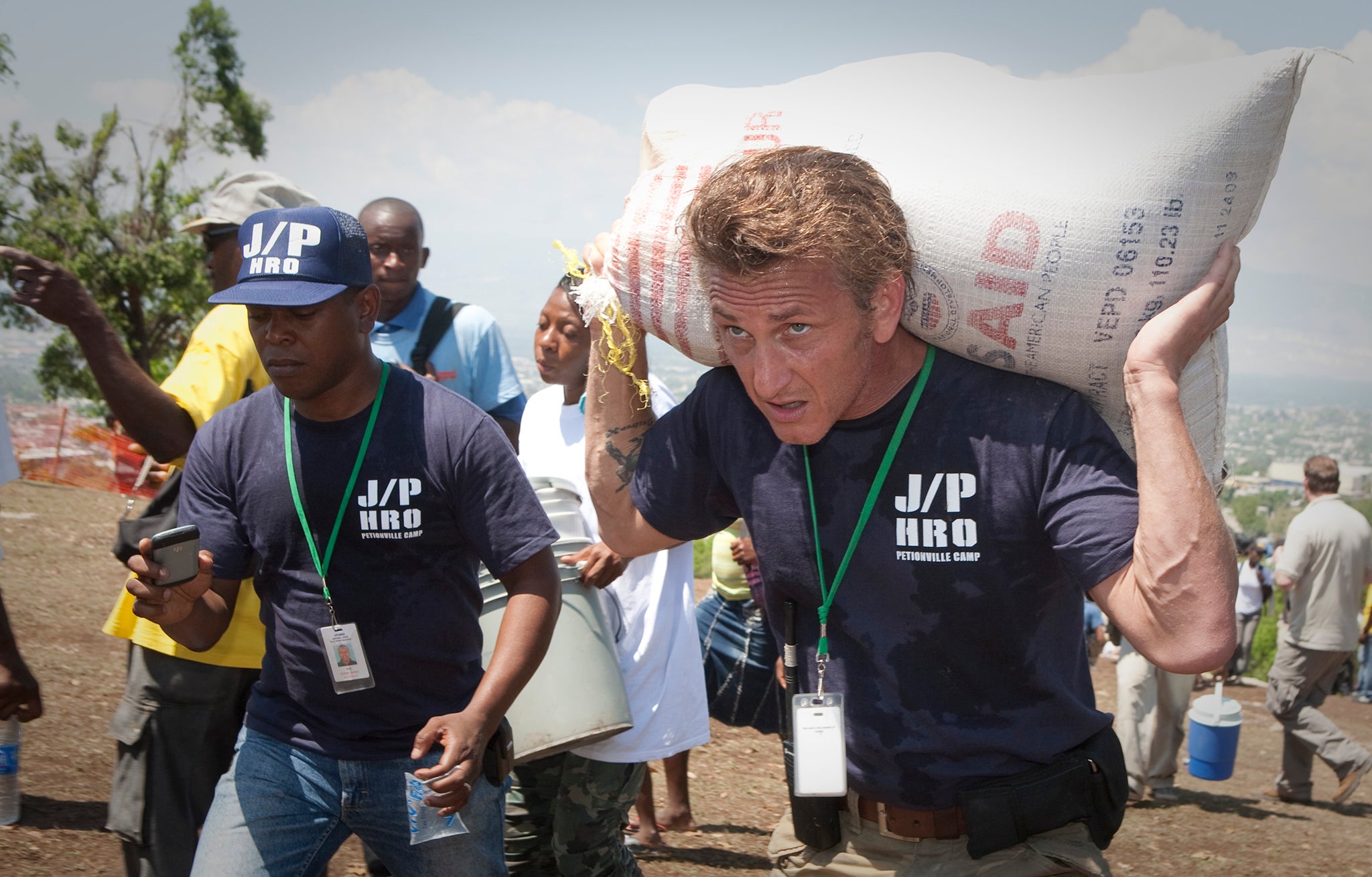 Actor Sean Penn carries a camp resident’s belongings as they prepare to be relocated after the 2010 Haiti earthquake