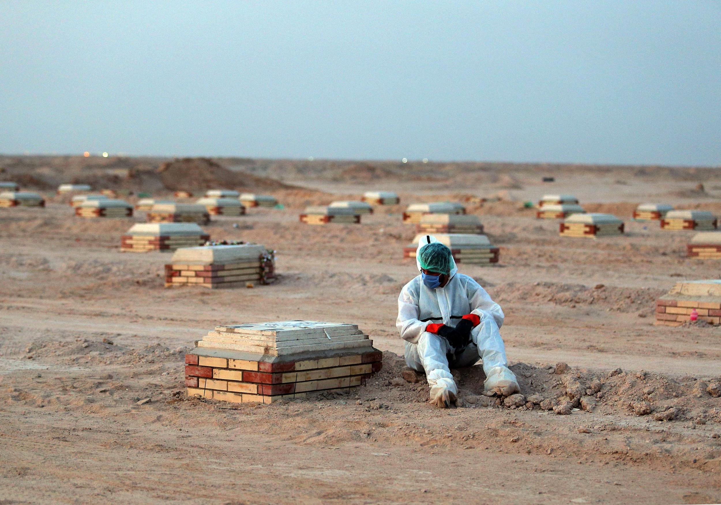 A man mourns over a tombstone at a cemetery for Covid-19 victims, 20km from the central Iraqi holy city of Najaf