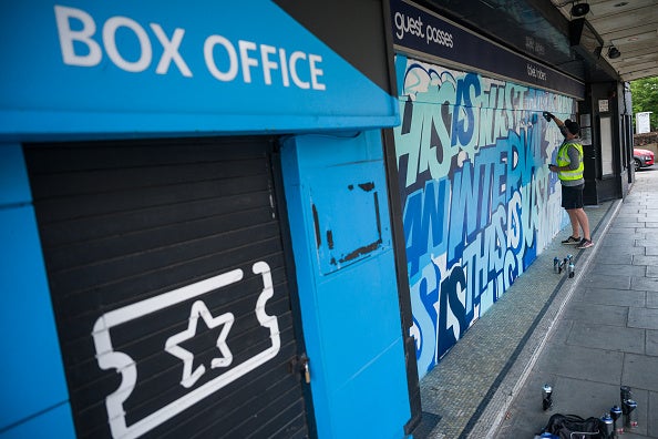 Street artist Captain Kris works on a mural on the temporary hoardings outside the O2 Forum in Kentish Town