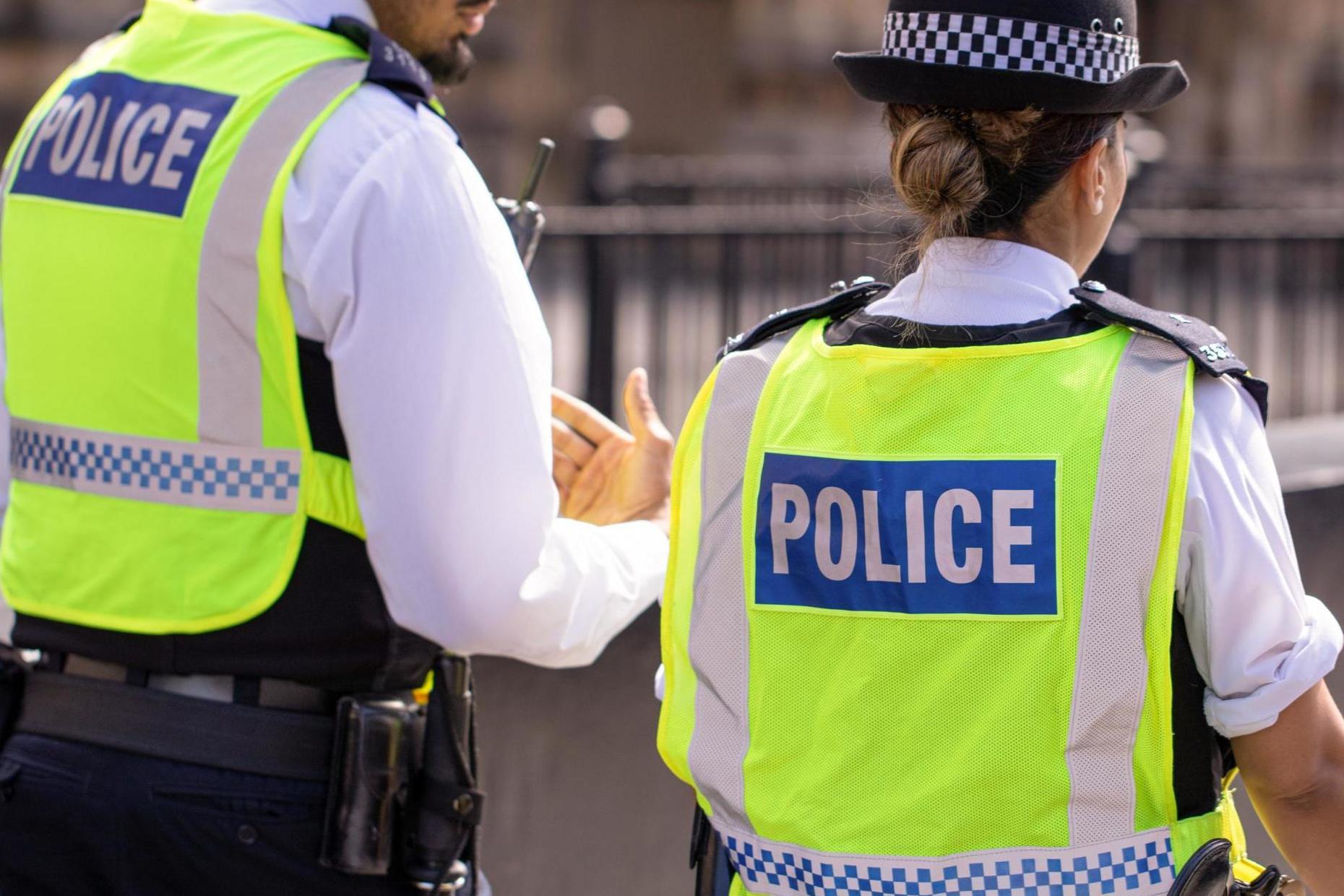 Male and female Asian metropolitan police officers patrol the crowds of tourists in Westminster, London