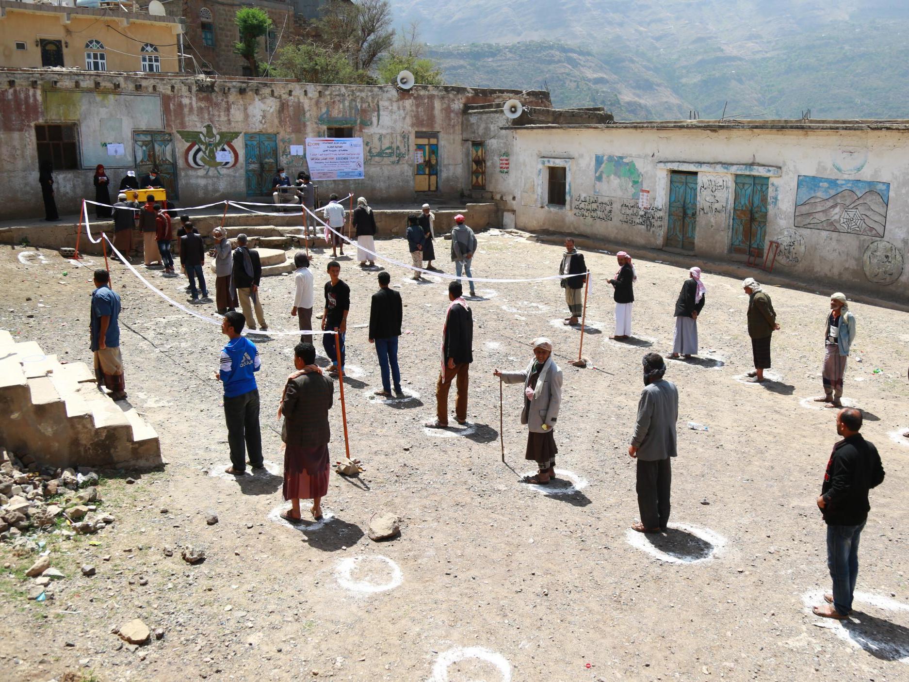 People queuing with social distancing measures at a food distribution facility in Ibb