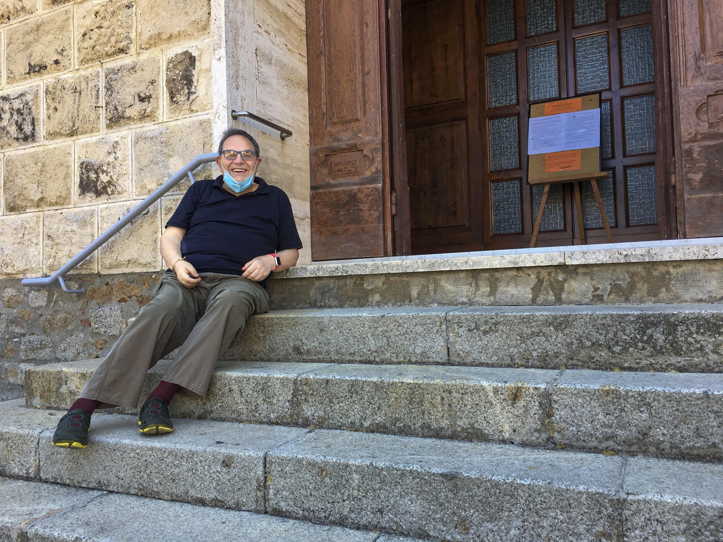 Reverend Lorenzo Pasquotti poses for photos on the steps of his church at the Giglio Island. Some 50 local mourners filled the pews for that funeral in Saints Lorenzo and Mamiliano Church, including a man from the continent that had Covid-19 infection