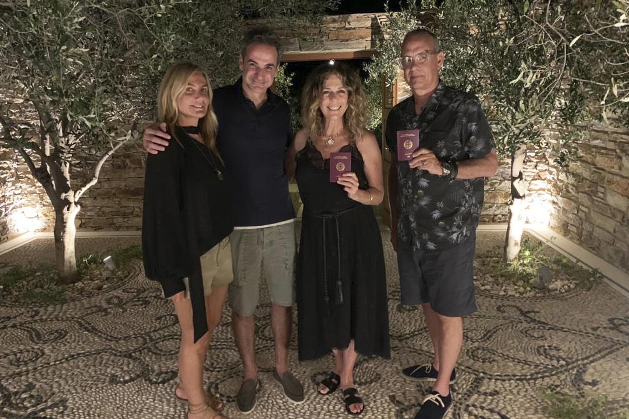 Greek Prime Minister Kyriakos Mitstotakis, second left, his wife Mareva Grabowski-Mitsotaki, left, pose next to Tom Hanks and his wife Rita Wilson holding up their new Greek passports, in the island of Antiparos, Greece on Saturday 25 July 2020.