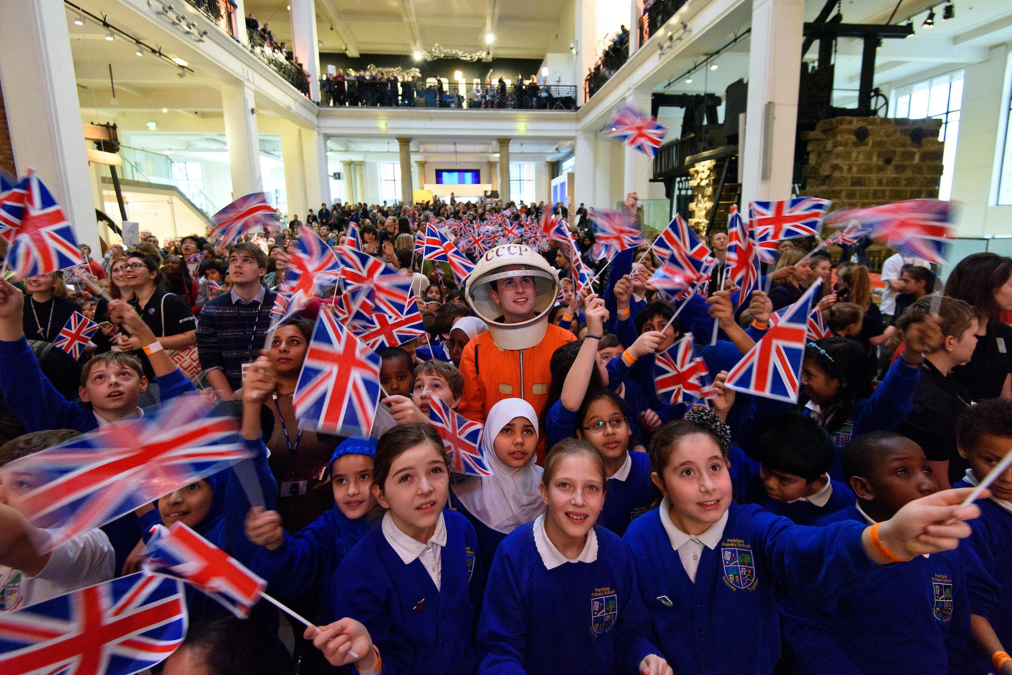 A man in a space suit watches a television with school children at the Science Museum ahead of the launch of space mission Principia from Baikonur Cosmodrome in Kazakhstan on December 15, 2015 in London, United Kingdom