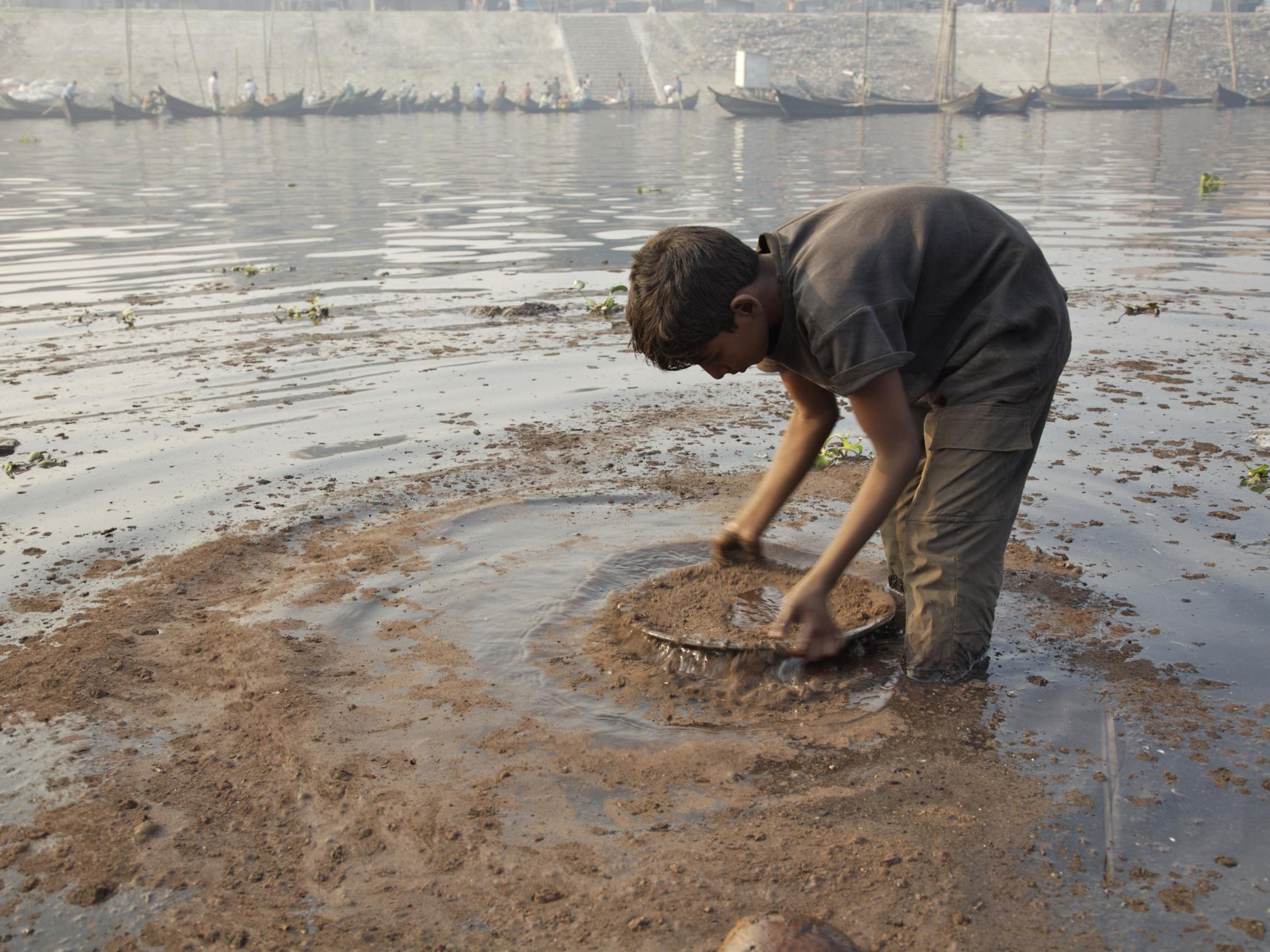 A young boy washes pieces of collected metal in a polluted river in Bangladesh, where there are more than 35 million cases of lead poisoning in children above the age of 5 years old, according to Unicef