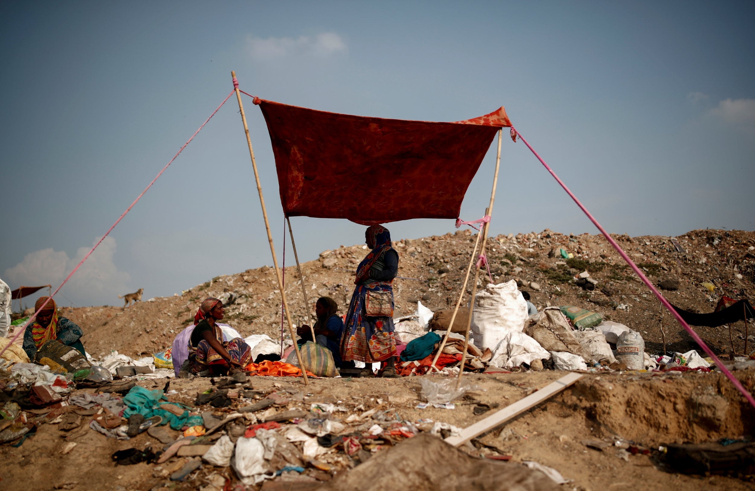 Bibi shields herself from the sun under a blanket with other waste collectors (Reuters)