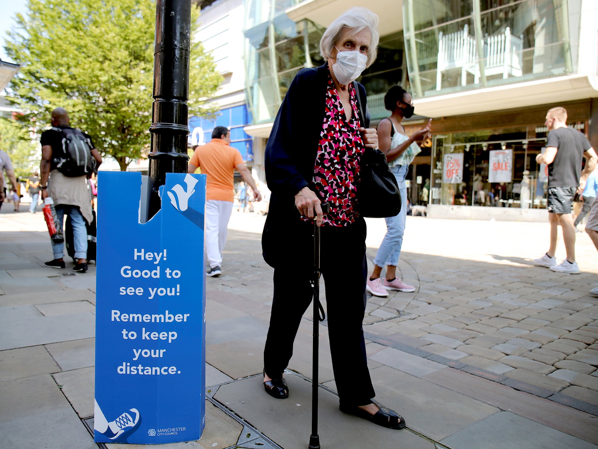 A woman wearing a protective mask walks down the street in Manchester as the city and surrounding areas face local restrictions amid a coronavirus outbreak.